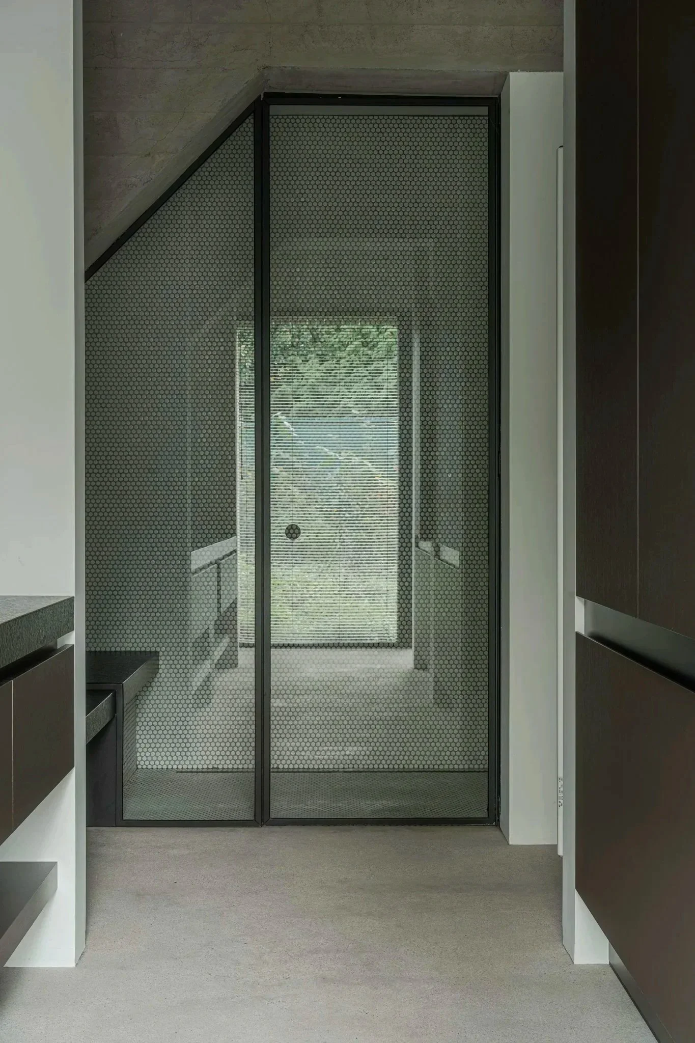 Modern kitchen with black cabinets, light gray walls, and a glass door with a screen door showing a view of greenery outside.