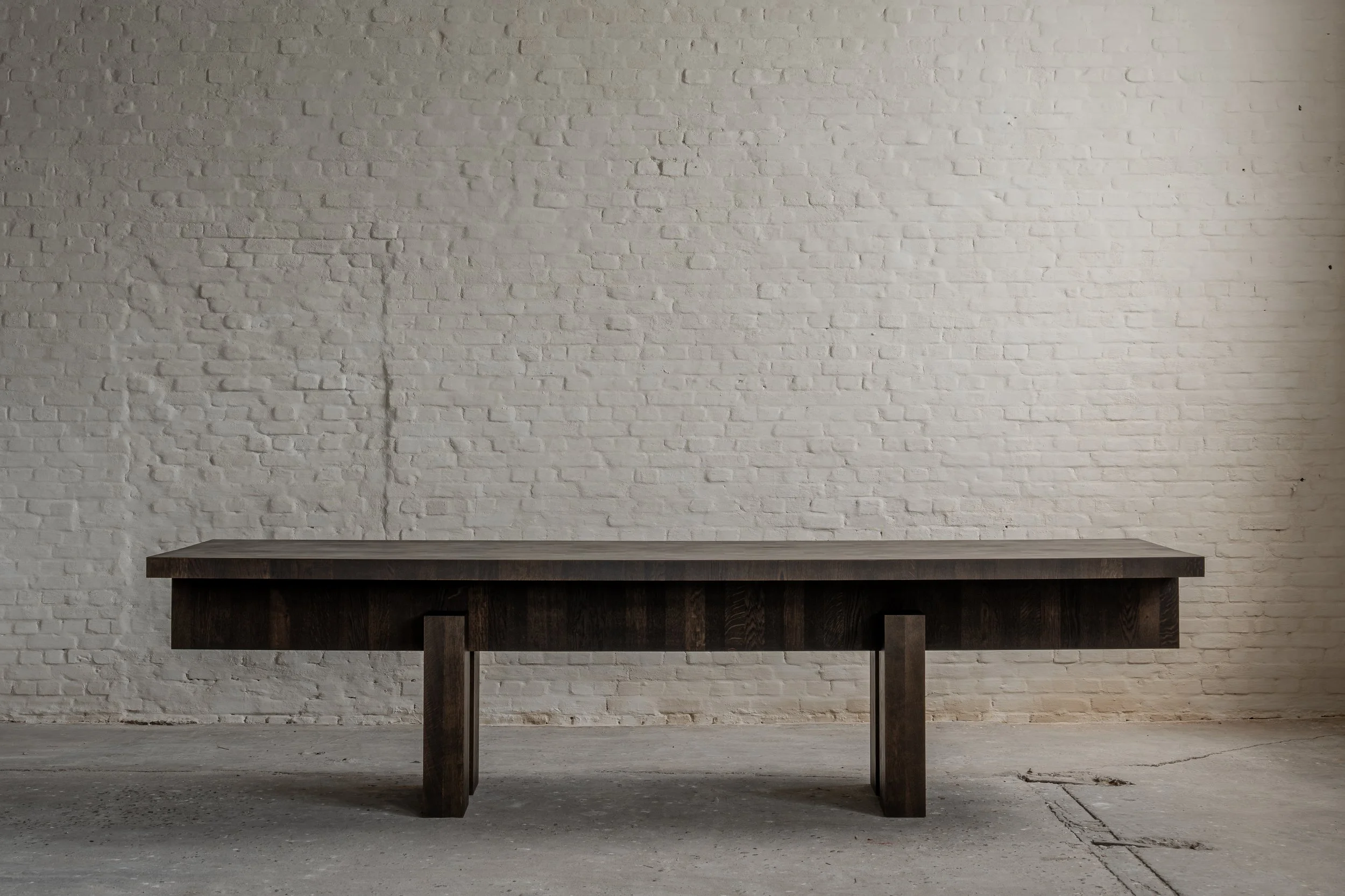 A dark wooden table against a white brick wall in an industrial-style room.