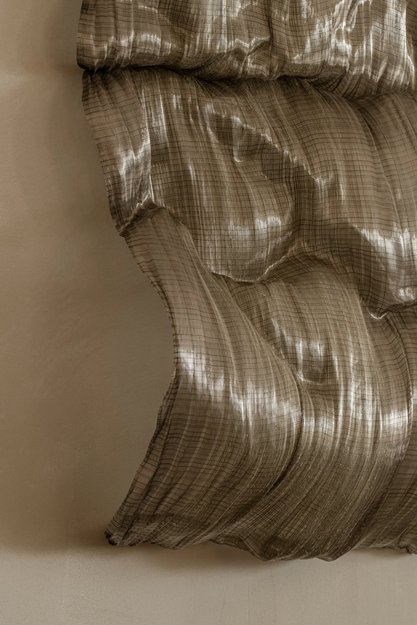 Close-up of a tufted, plaid fabric curtain with shiny, silky texture.