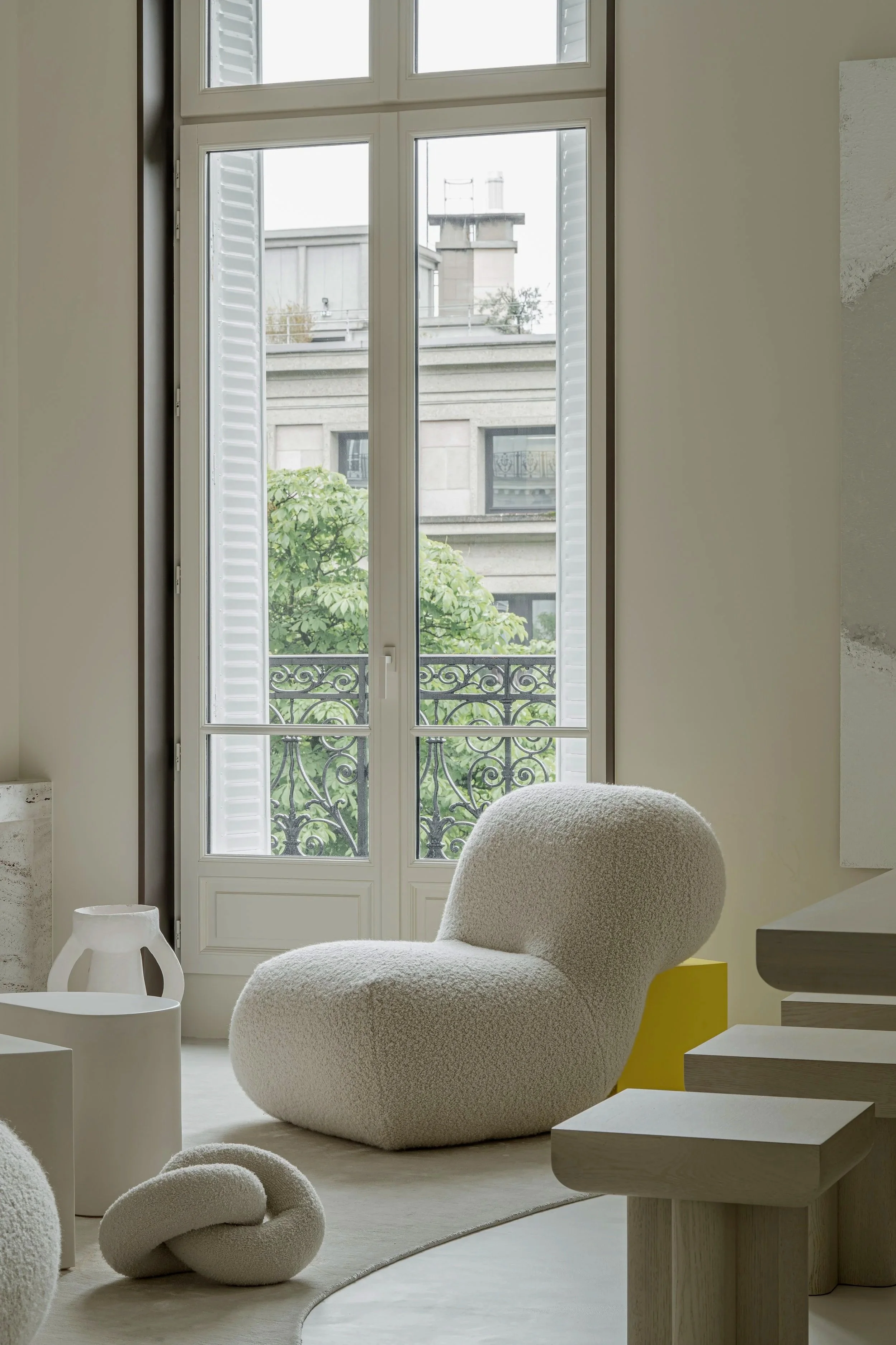 Interior of a modern room with a large window, a cozy beige lounge chair, and minimal decor.