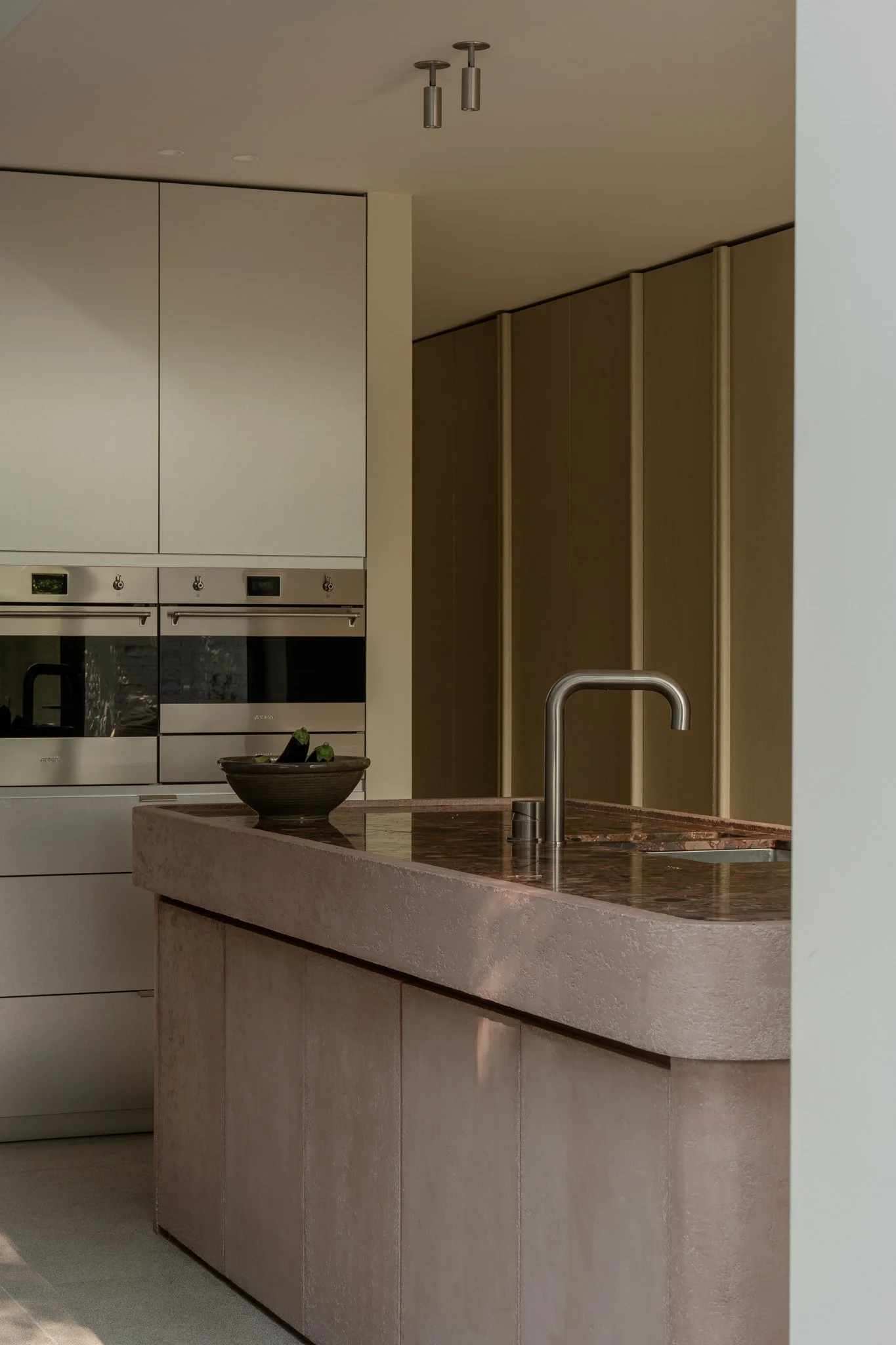 Modern kitchen with beige cabinets, brown marble countertop, and built-in appliances.