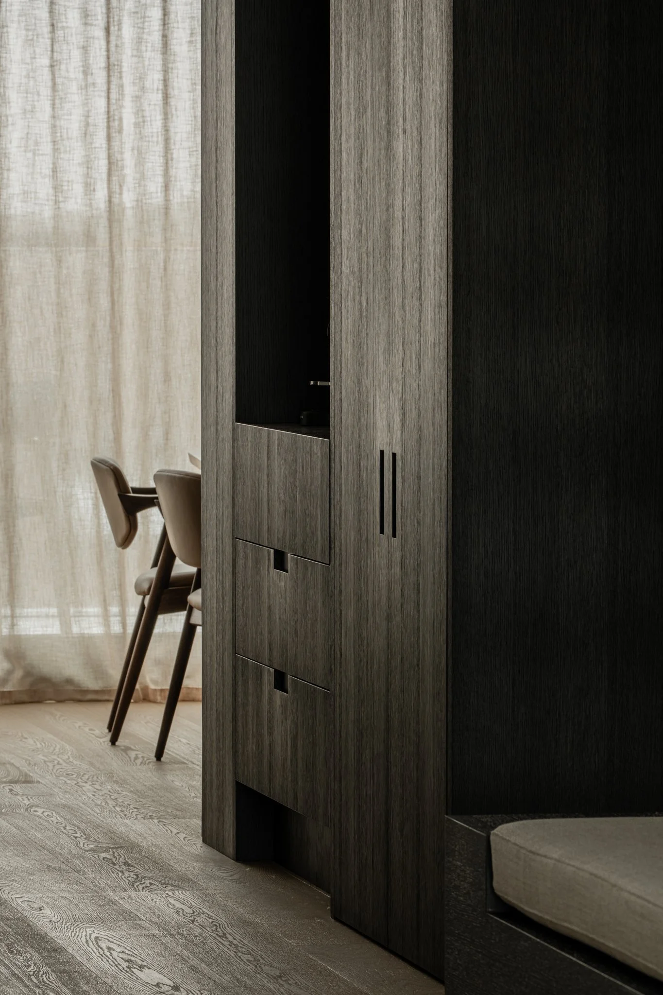 Modern living space with dark wooden furniture, a chair, and a window with beige curtains.