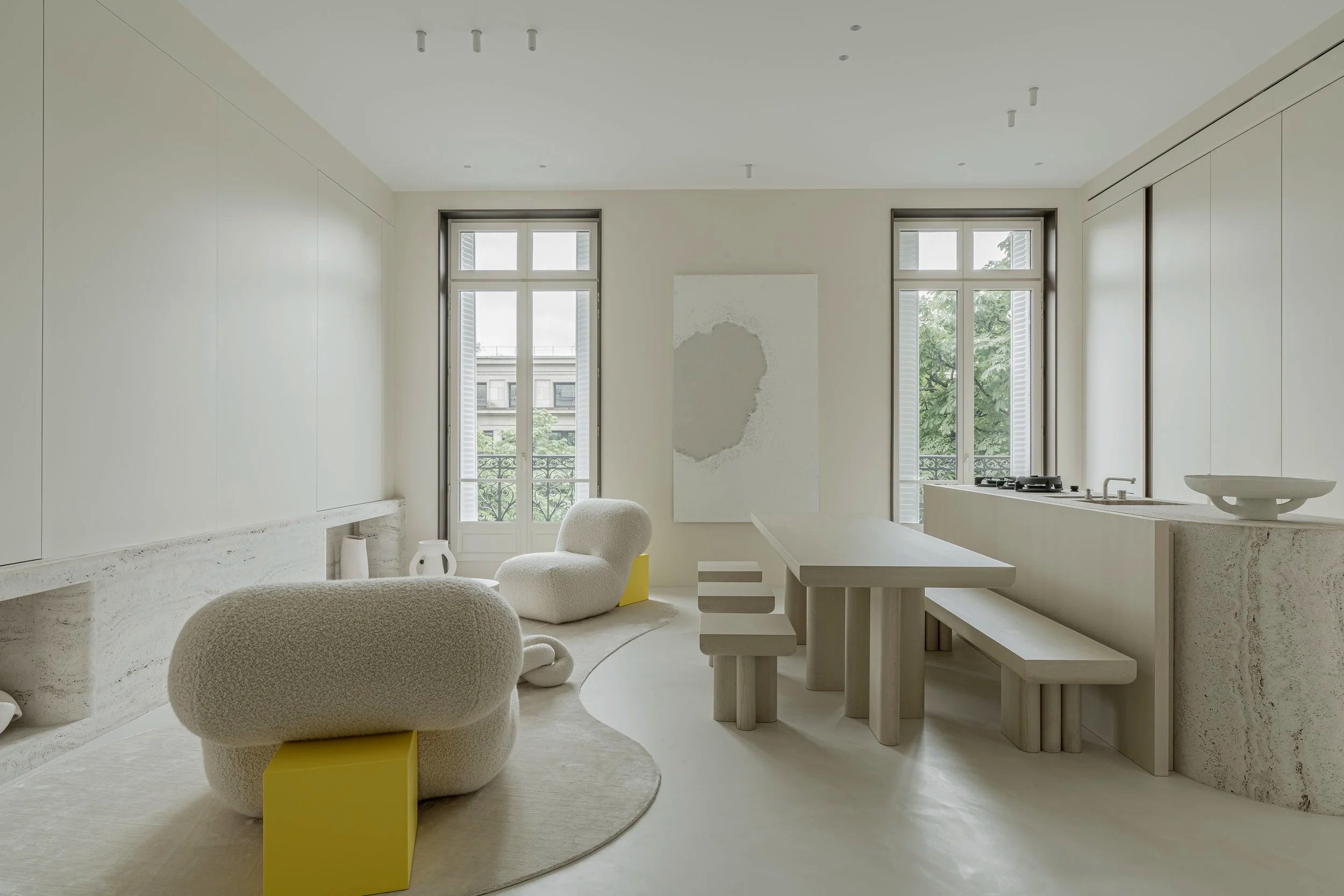 Minimalist living room with beige furniture, large windows, and simple decor.