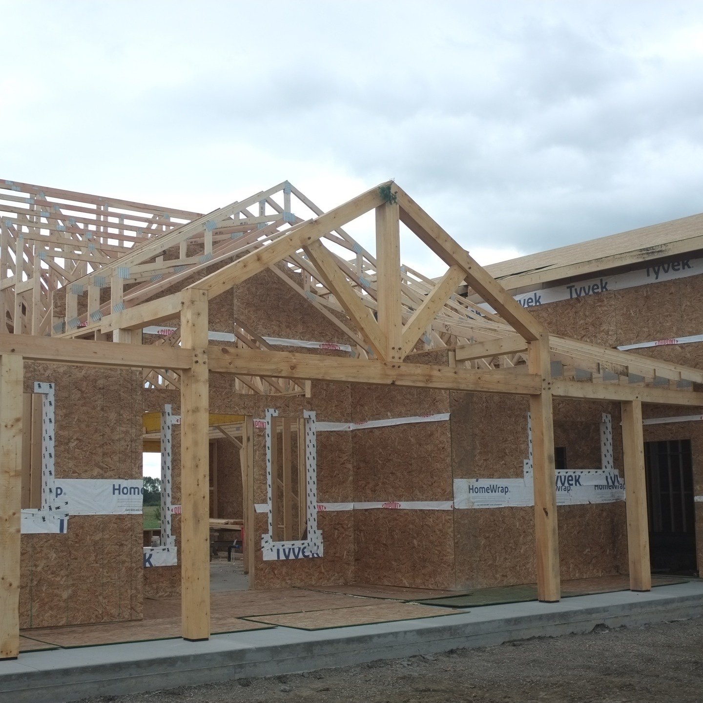 Back in August we put up these two king post truss porches that tie into the conventional framing on this new build. Many thanks to @central_valley_furniture for his immense help with this one. Please excuse the Tyvek and OSB...