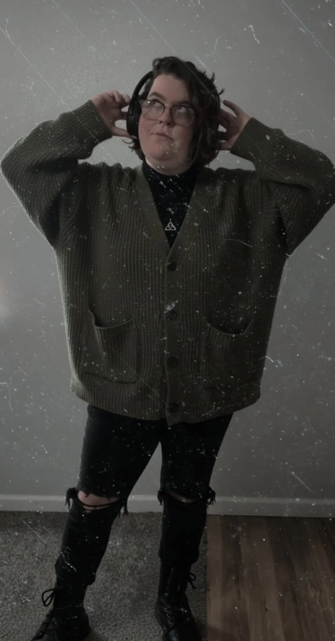 Rachel, founder of Oktober Designs, wearing headphones and an oversized cardigan against a textured light background