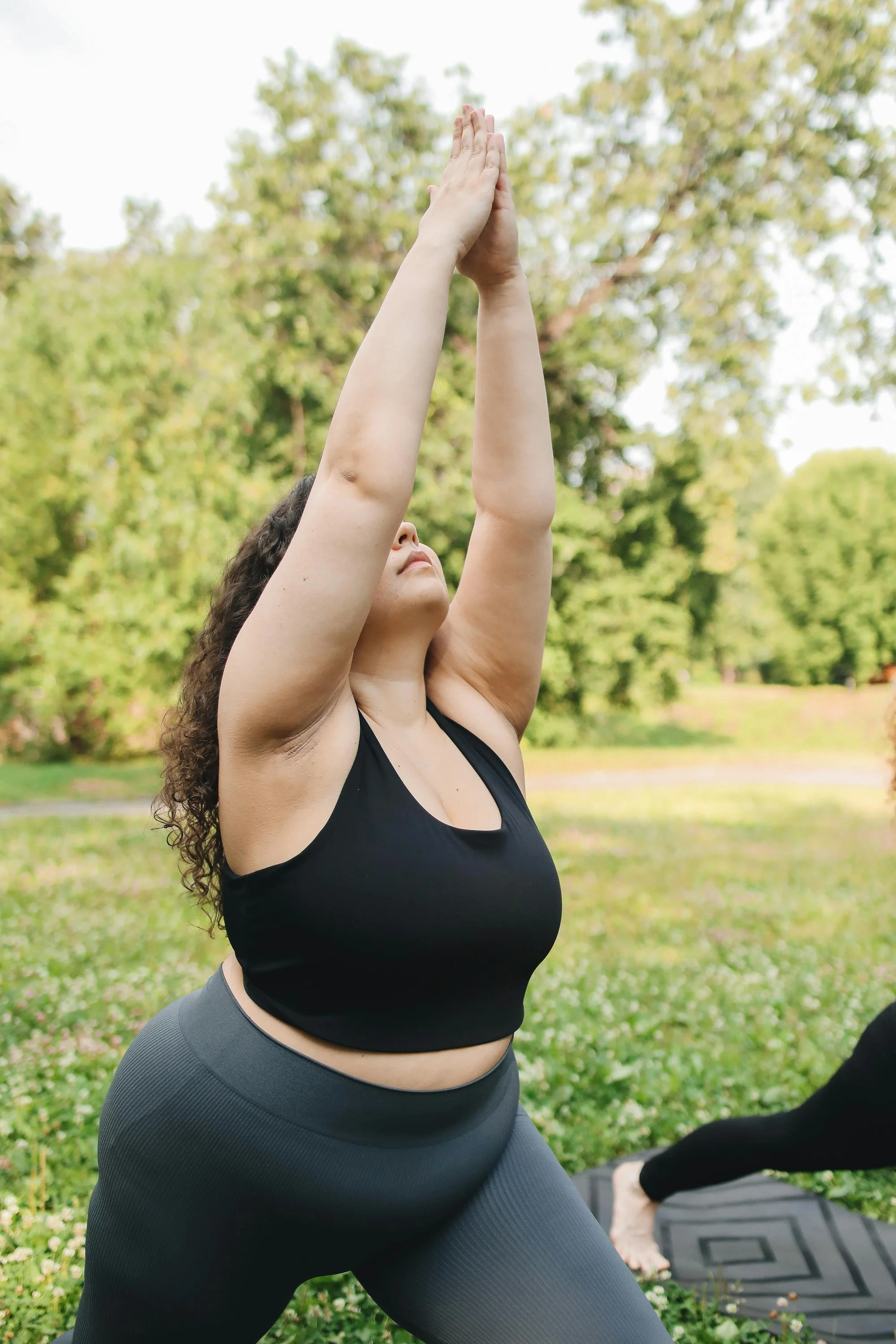 A woman stretches her arms upward with intention—capturing a moment of release and reconnection, reflecting how movement can support healing from exhaustion and burnout.