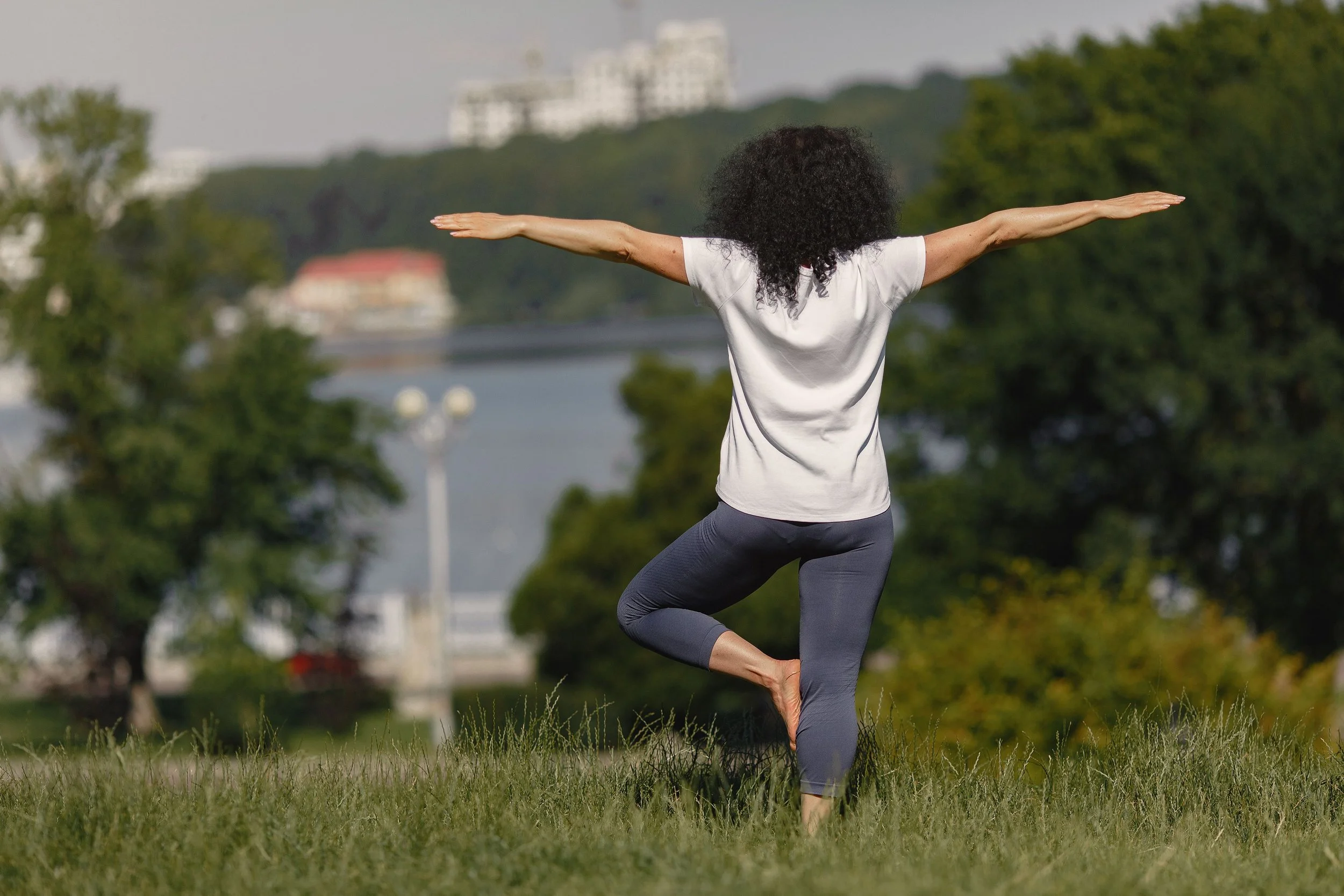 Woman doing gentle movement outdoors representing trauma-informed exercise for nervous system regulation