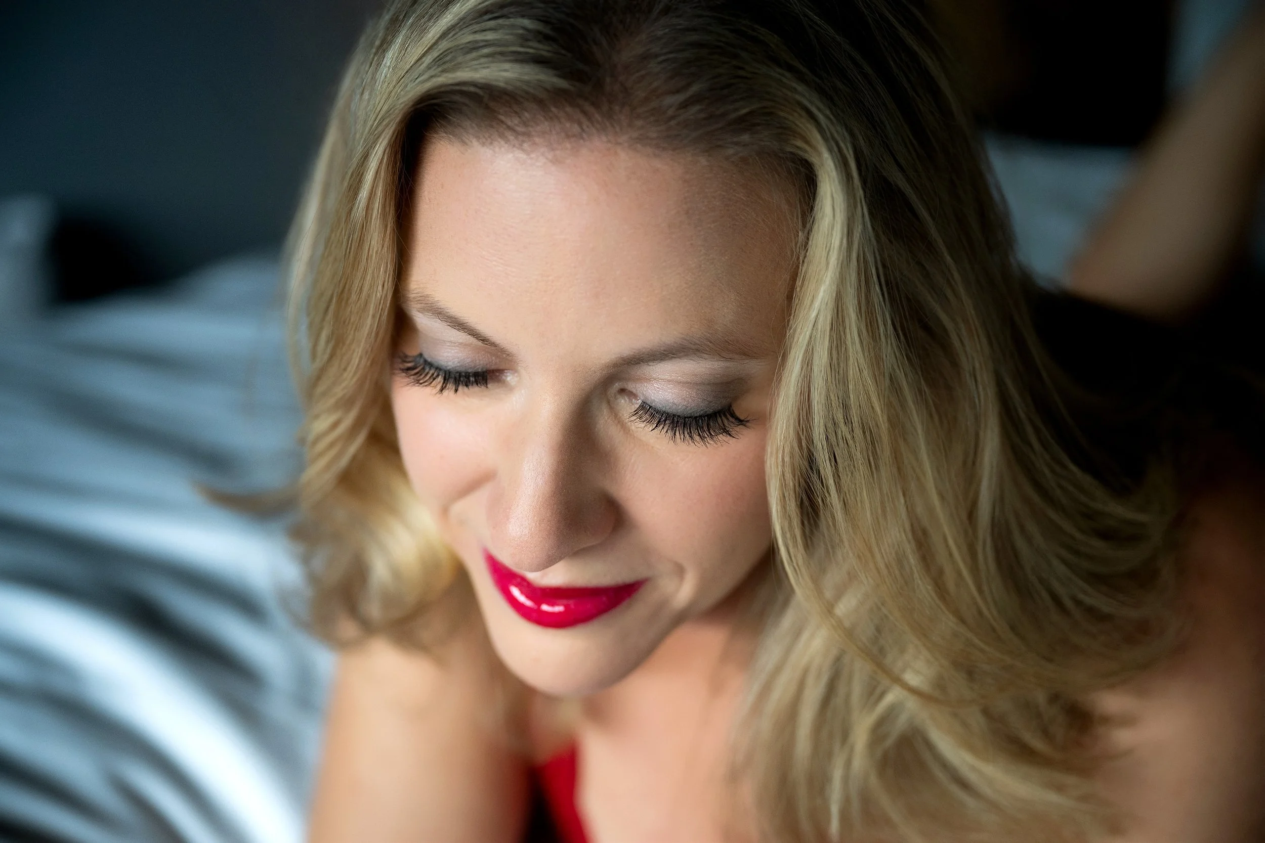 Woman over 40, quietly poised with red lips and full lashes, glancing down, by Eye Candy Boudoir, NY