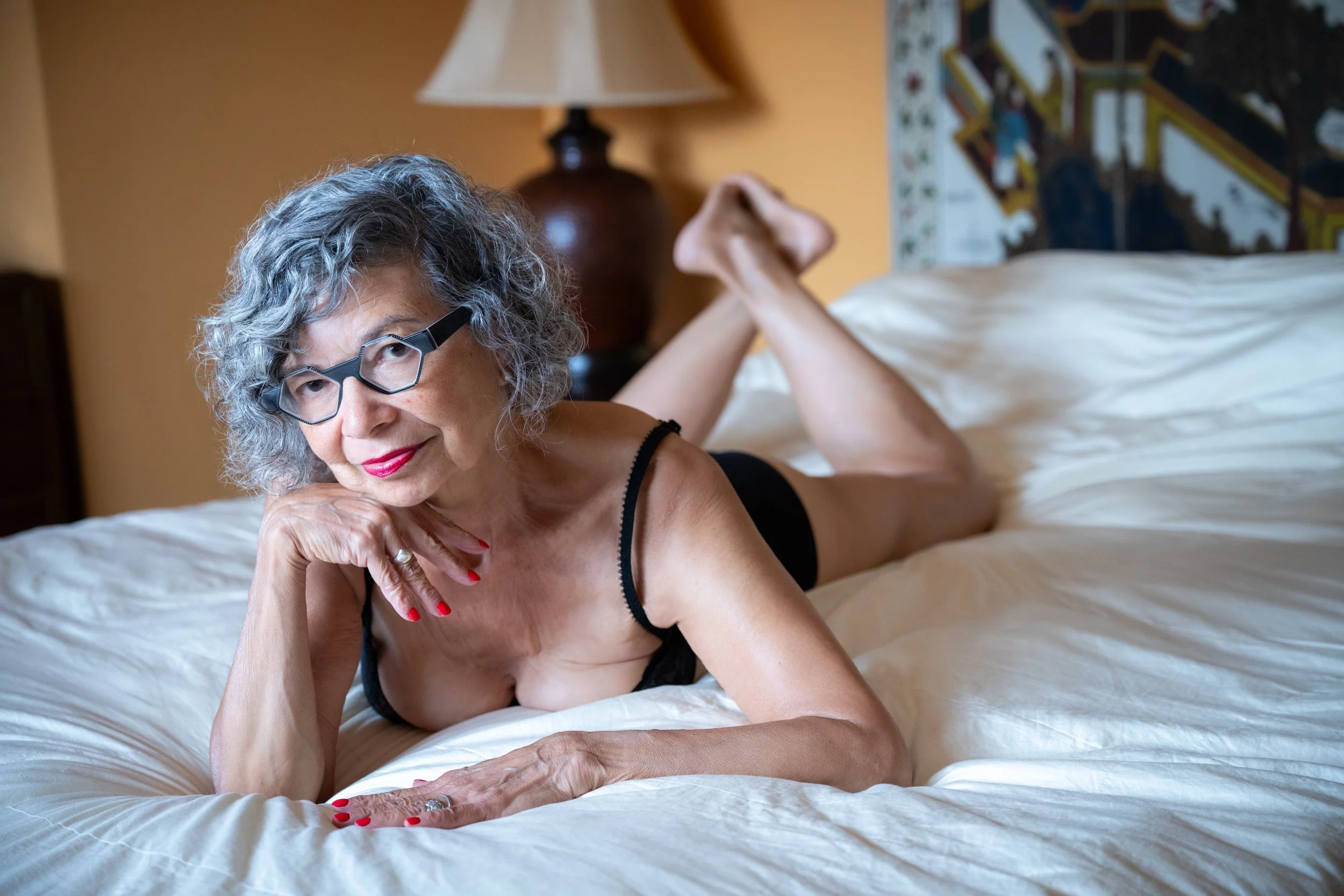 Boudoir portrait of a mature and confident woman, posed in a bedroom in New York City. 