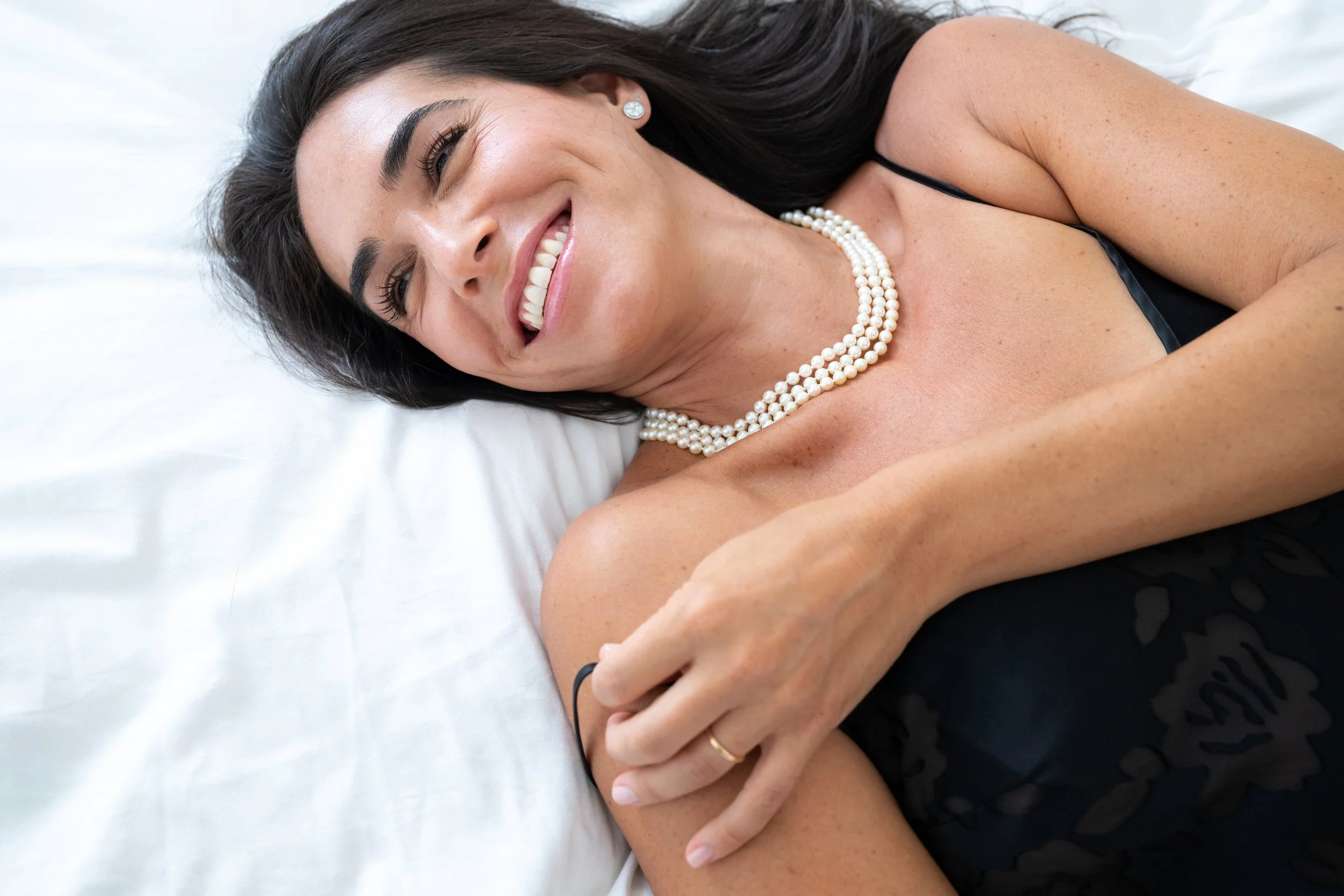 Playful, smiling woman gently adjusting her lingerie strap by Eye Candy Boudoir, Westchester, NY