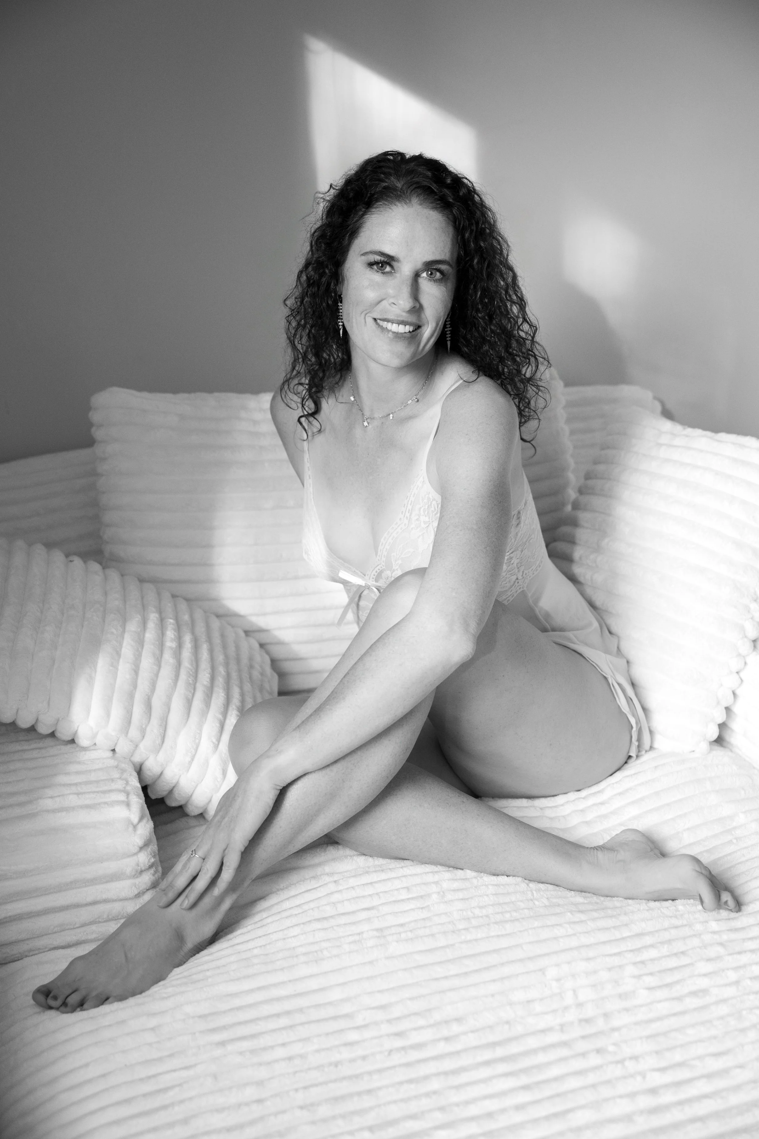 Woman seated on a chair in lingerie, her presence grounded, powerful, and entirely her own.