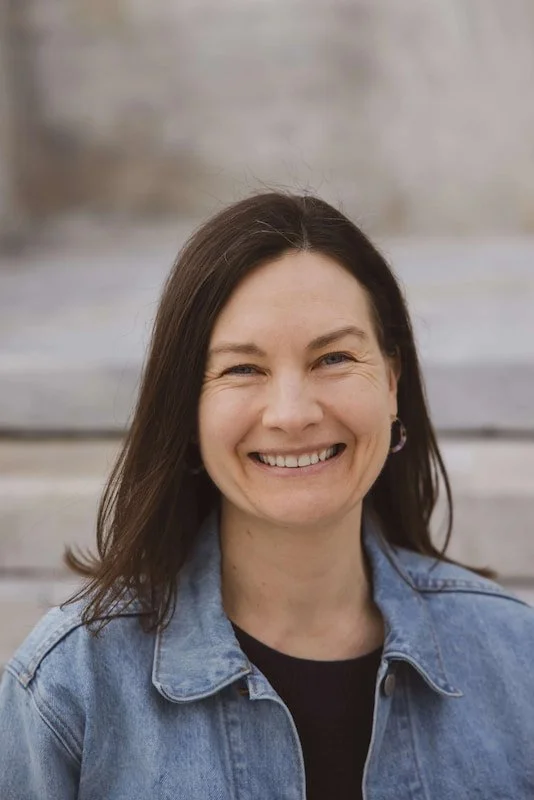 Rebecca, Therapist at Rebecca White Counseling, is outside wearing a jean jacket smiling into the camera