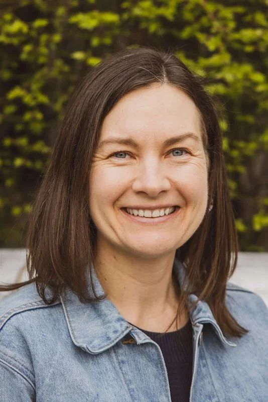 Rebecca, Therapist at Rebecca White Counseling, is outside wearing a jean jacket smiling into the camera