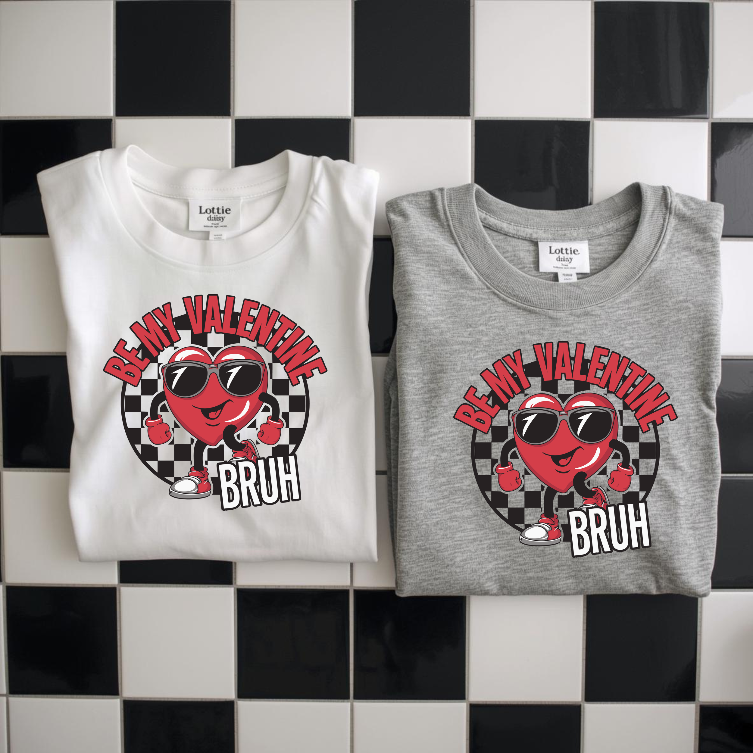 Two folded t-shirts, one white and one gray, with a graphic of a smiling heart wearing sunglasses and sneakers, holding fists up. The text on the white shirt says 'BE MY VALENTINE BRUH' and the text on the gray shirt says the same.