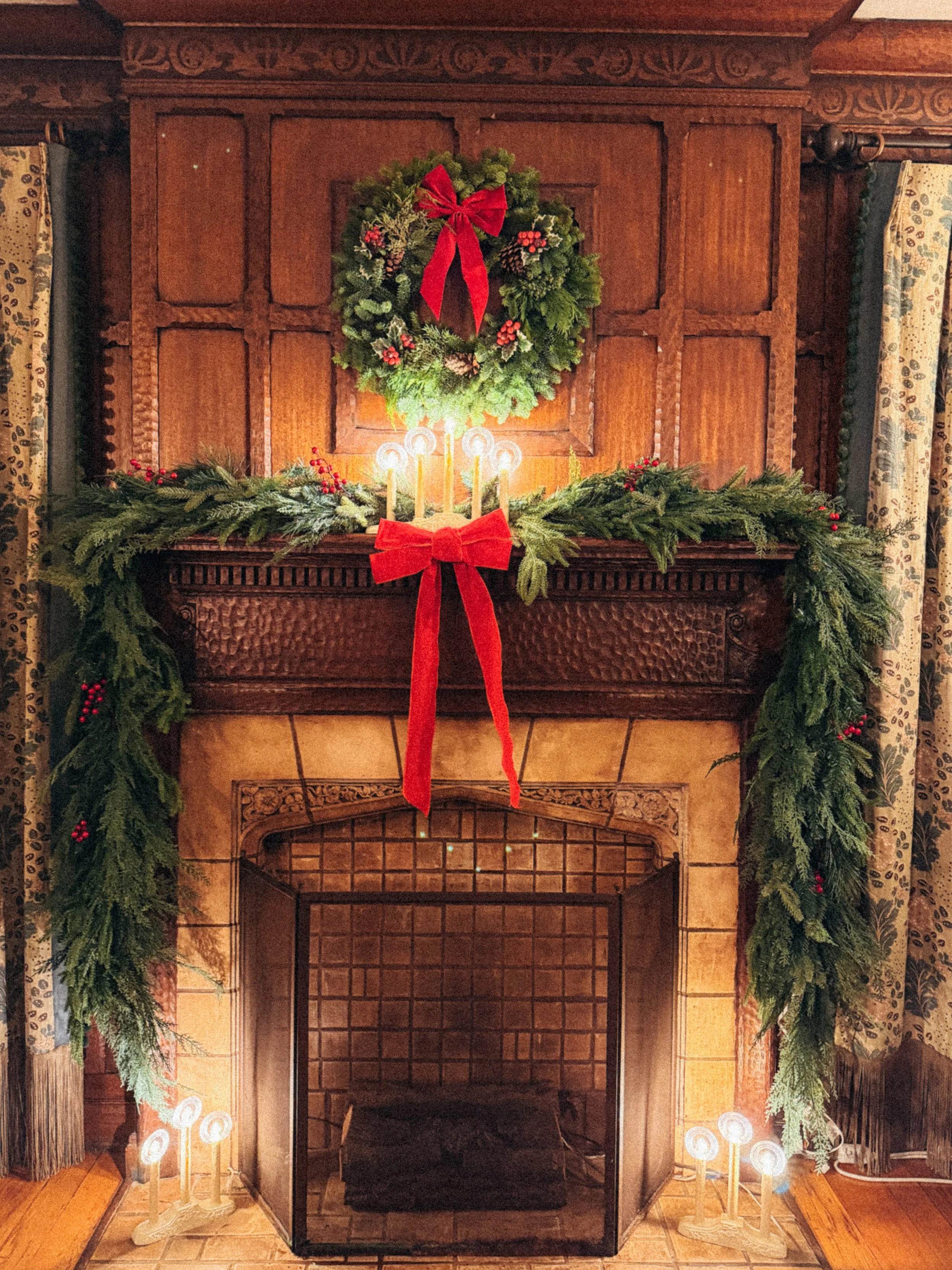 Christmas decorated fireplace with a wreath, garland, and candles.