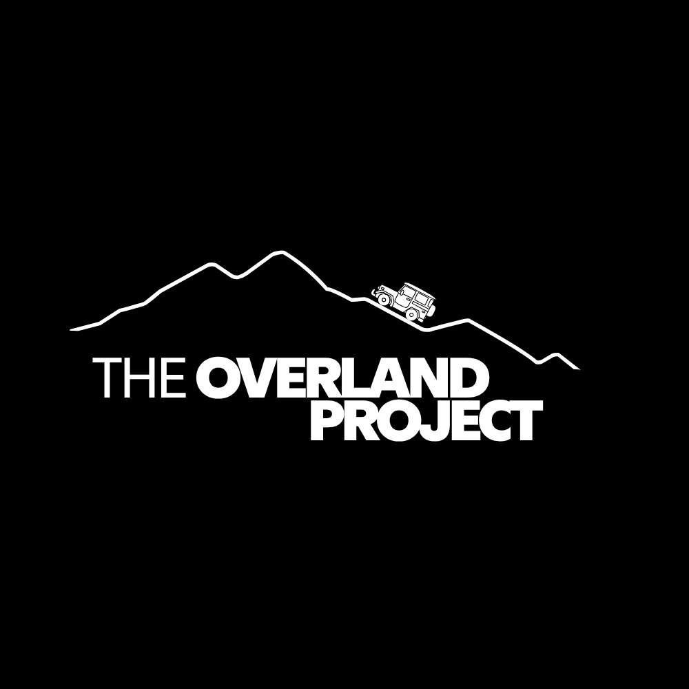 Black and white graphic featuring a mountain range with a vehicle on a trail and the text "The Overland Project" in bold lettering.