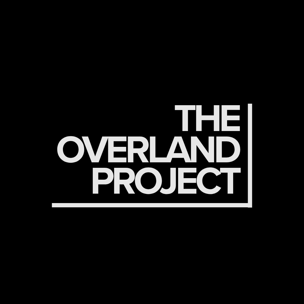 Logo with the words 'The Overland Project' in gray text on a black background, with lines framing the text.