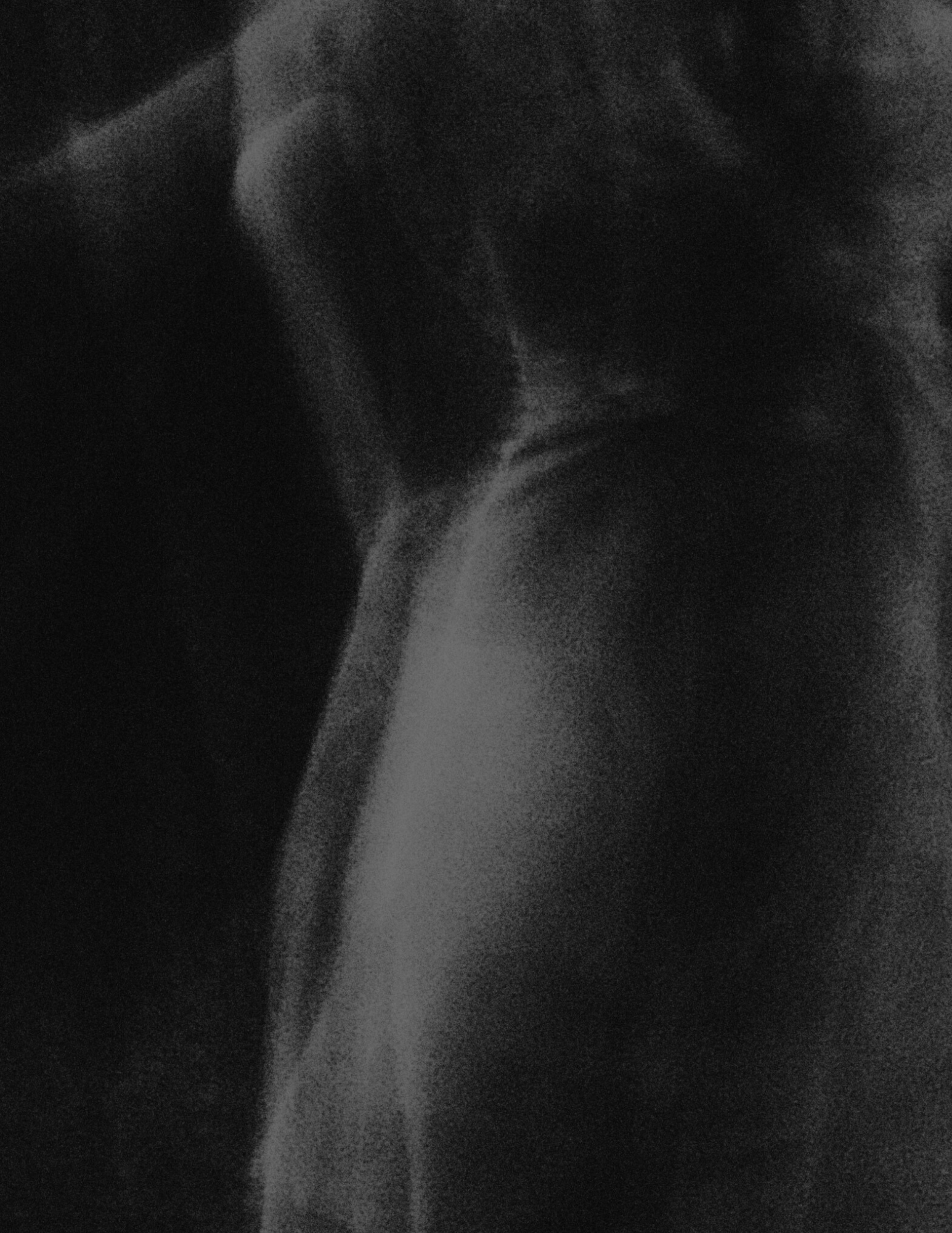 Black and white, close-up, grainy photo of a person in makeup, wearing a hat and looking downward.