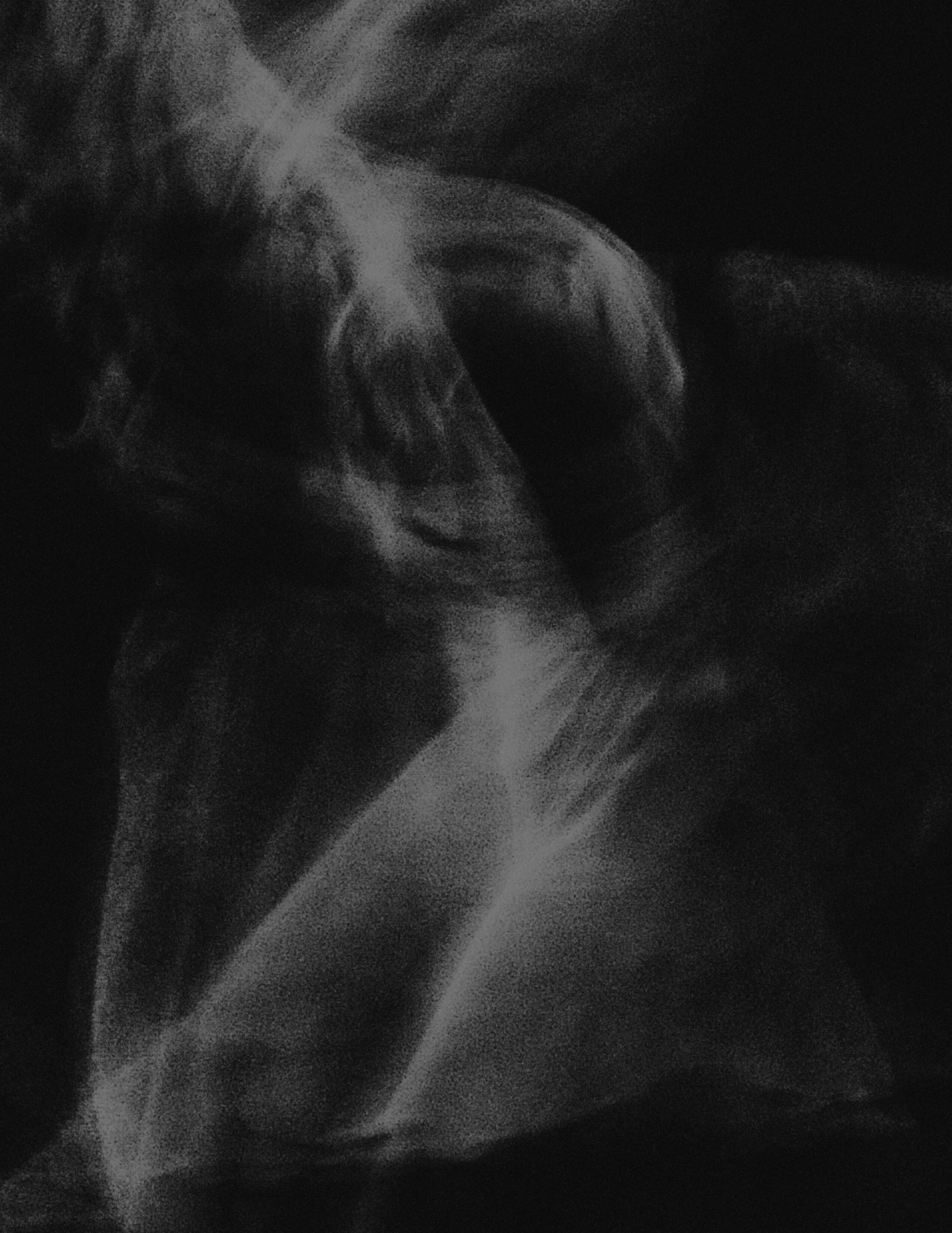 A black and white photograph of a woman with curly hair, looking downward, with her bare shoulder and part of her chest visible.