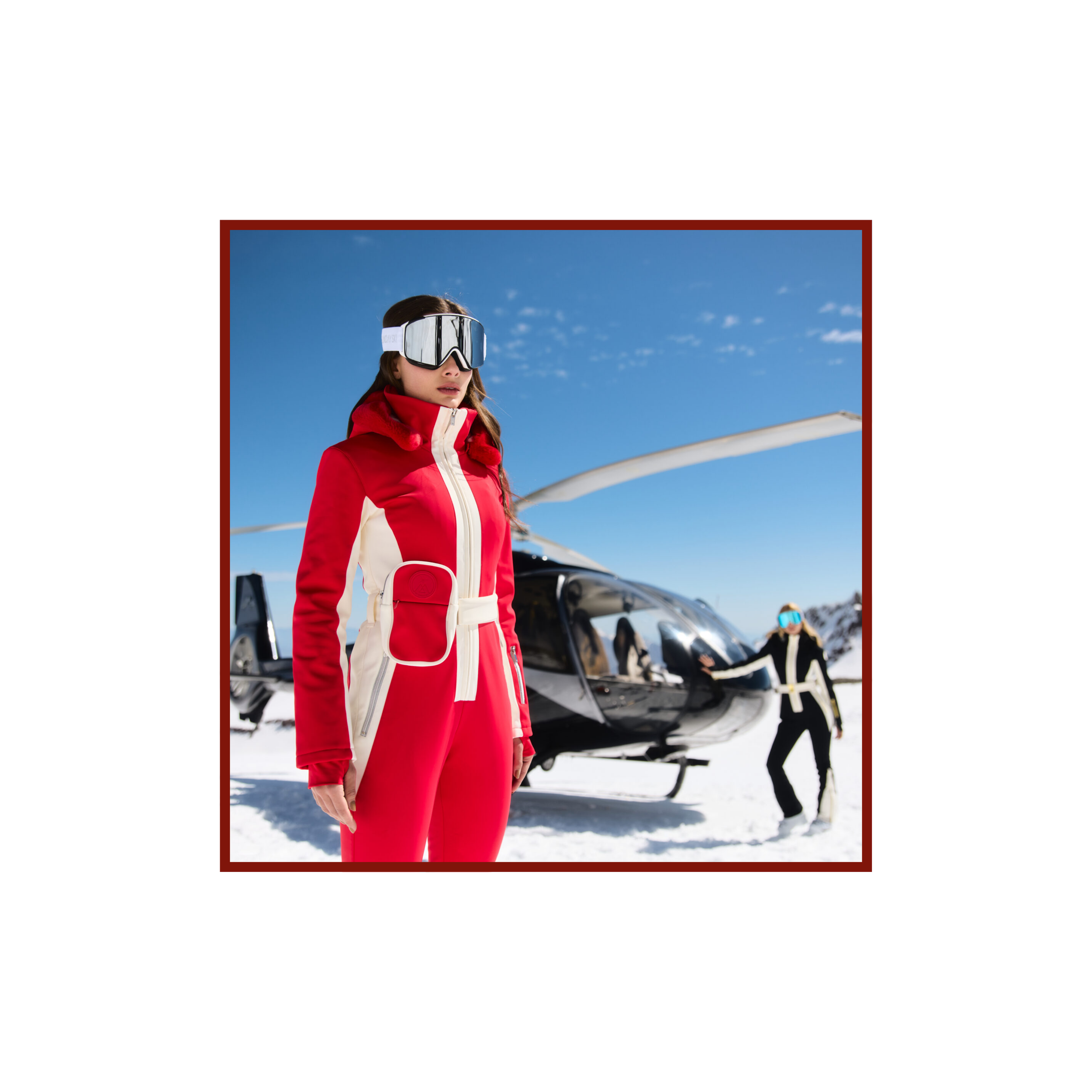 Skier in a red and white My Sunday Ski suit beside a helicopter on a snowy mountain.