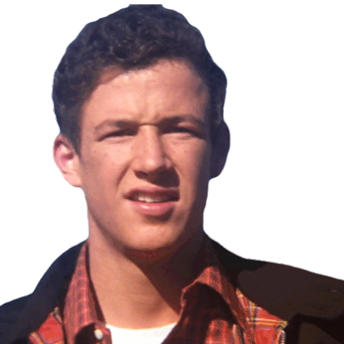 Een jonge man met kort, donker haar en een lichte huid, draagt een rood-geruit overhemd en een donker jack, staat buiten tegen een lichtkleurige achtergrond.