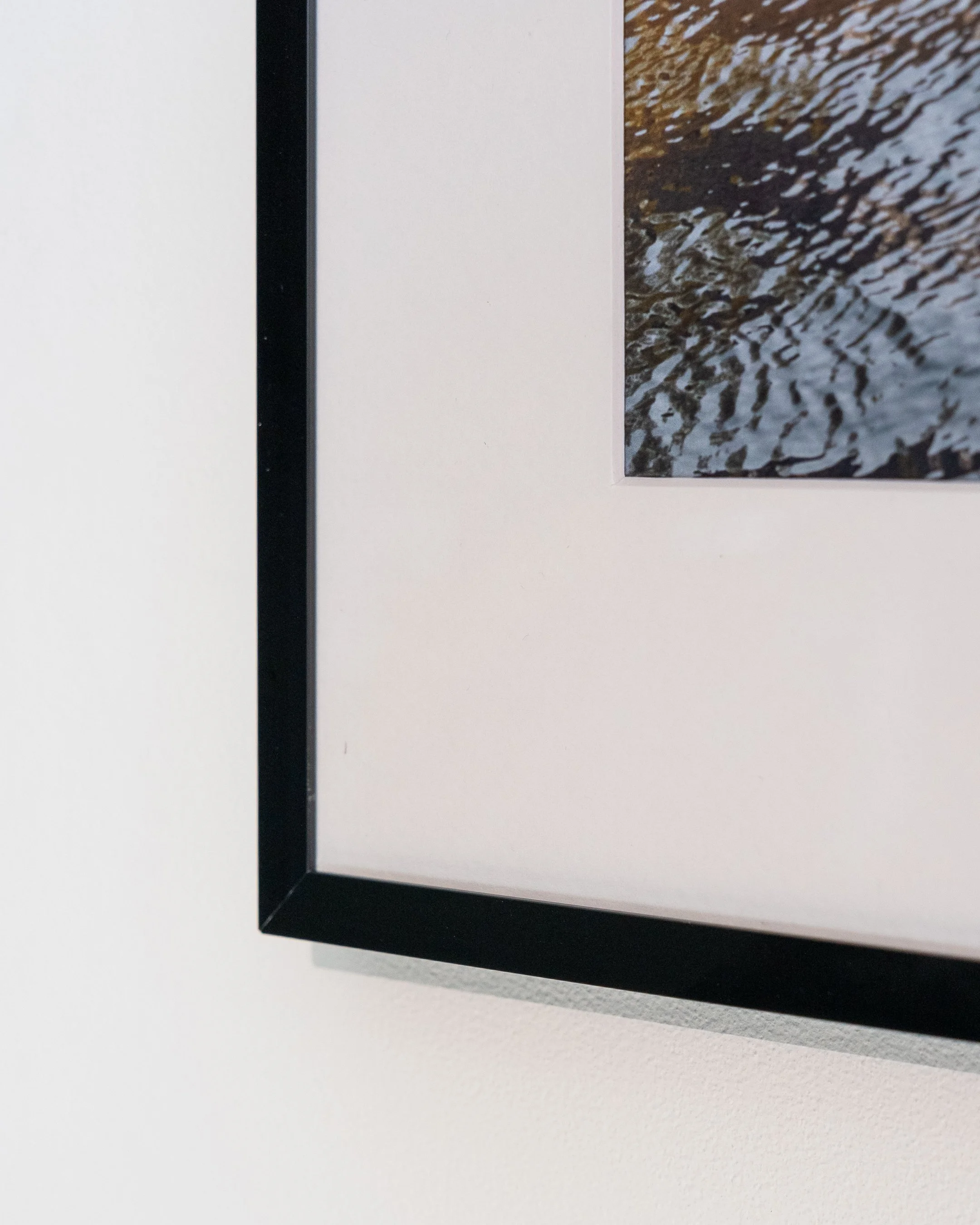 Deel van een ingelijste foto met een zwart frame en daarop een afbeelding van golvend water.