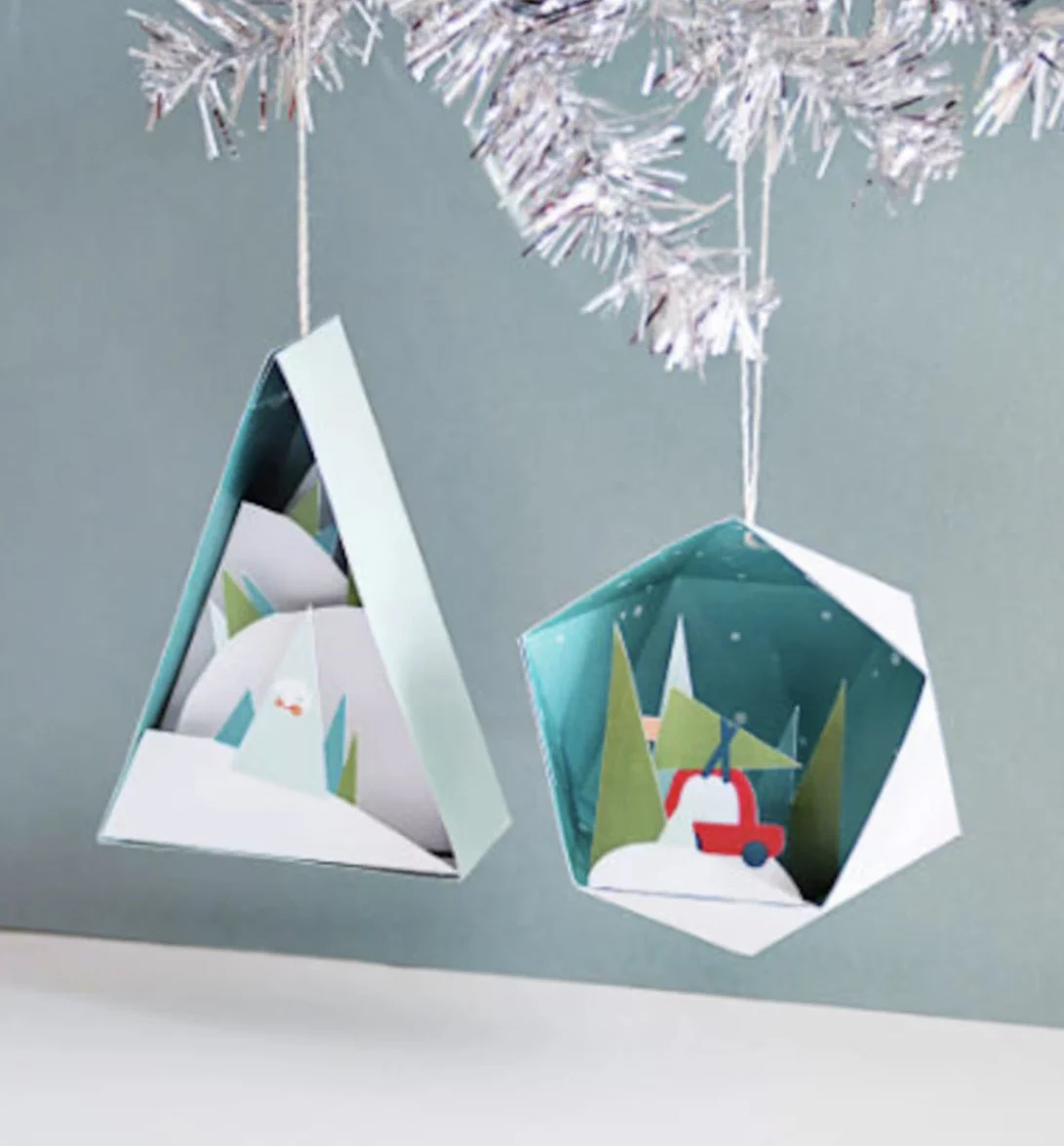 Holiday paper craft handmade ornaments with winter scene illustrations, hanging from silver tinsel. Author-Illustrator Mari Richards picture book illustration and art full of monsters, animals, quirky kids.