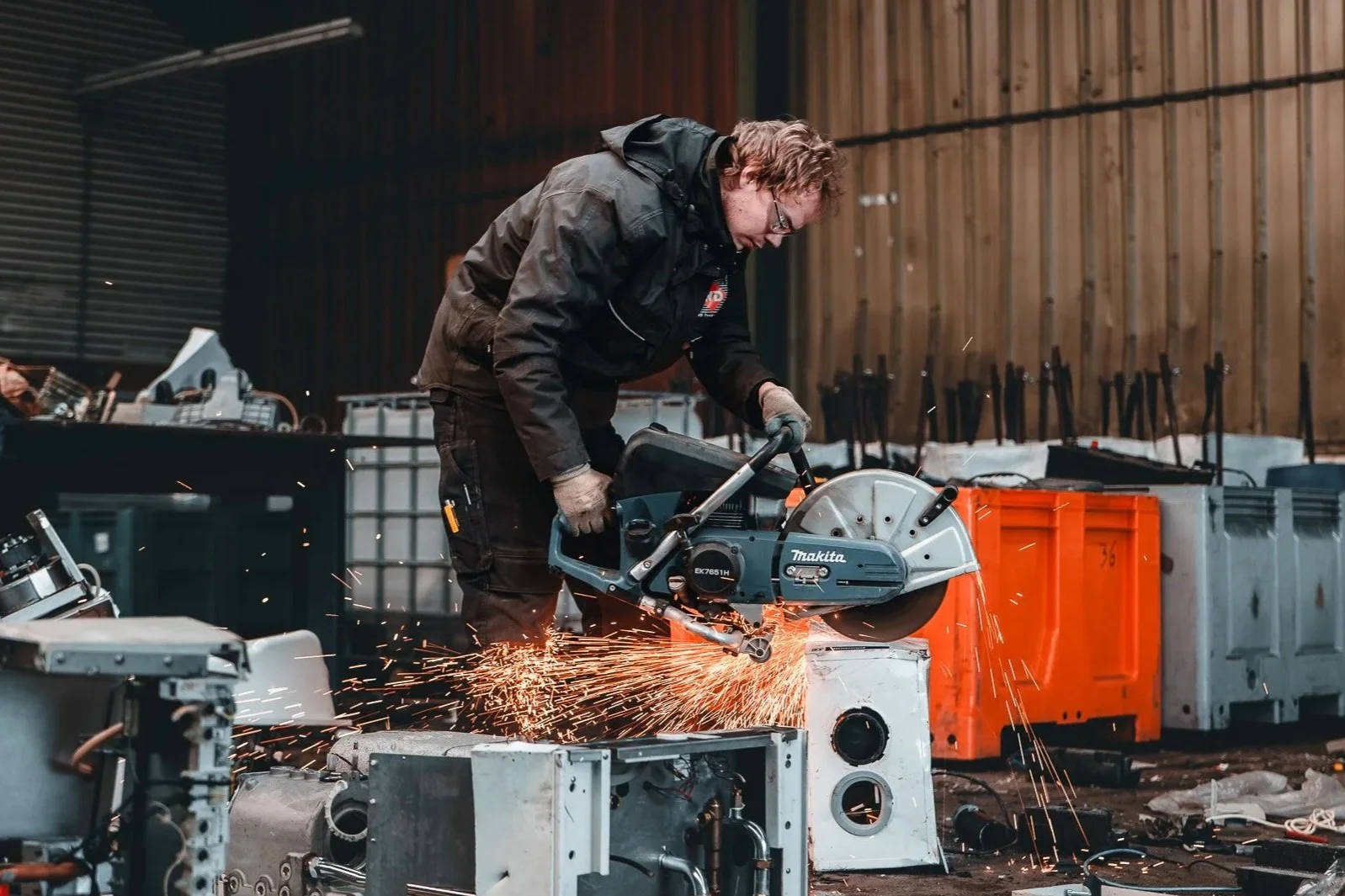 Man snijdt met een zijdezagen in een industriële werkplaats, er vliegen vonken.