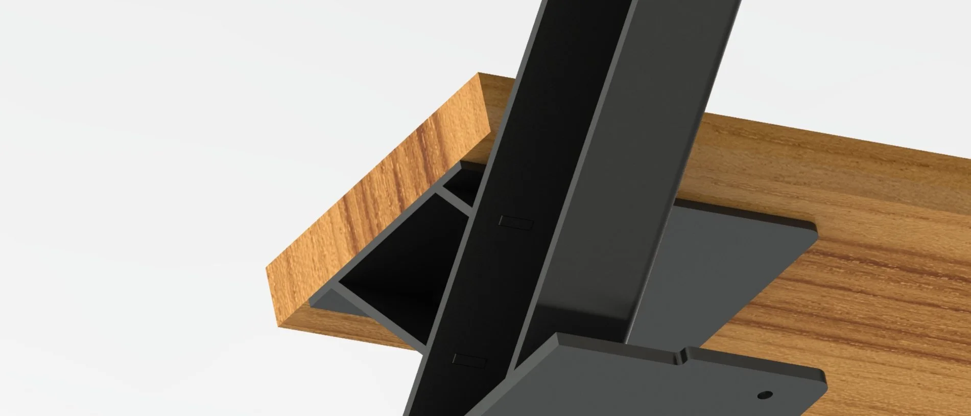 Close-up of a black metal office desk monitor stand with a wooden surface beneath it, viewed from above.