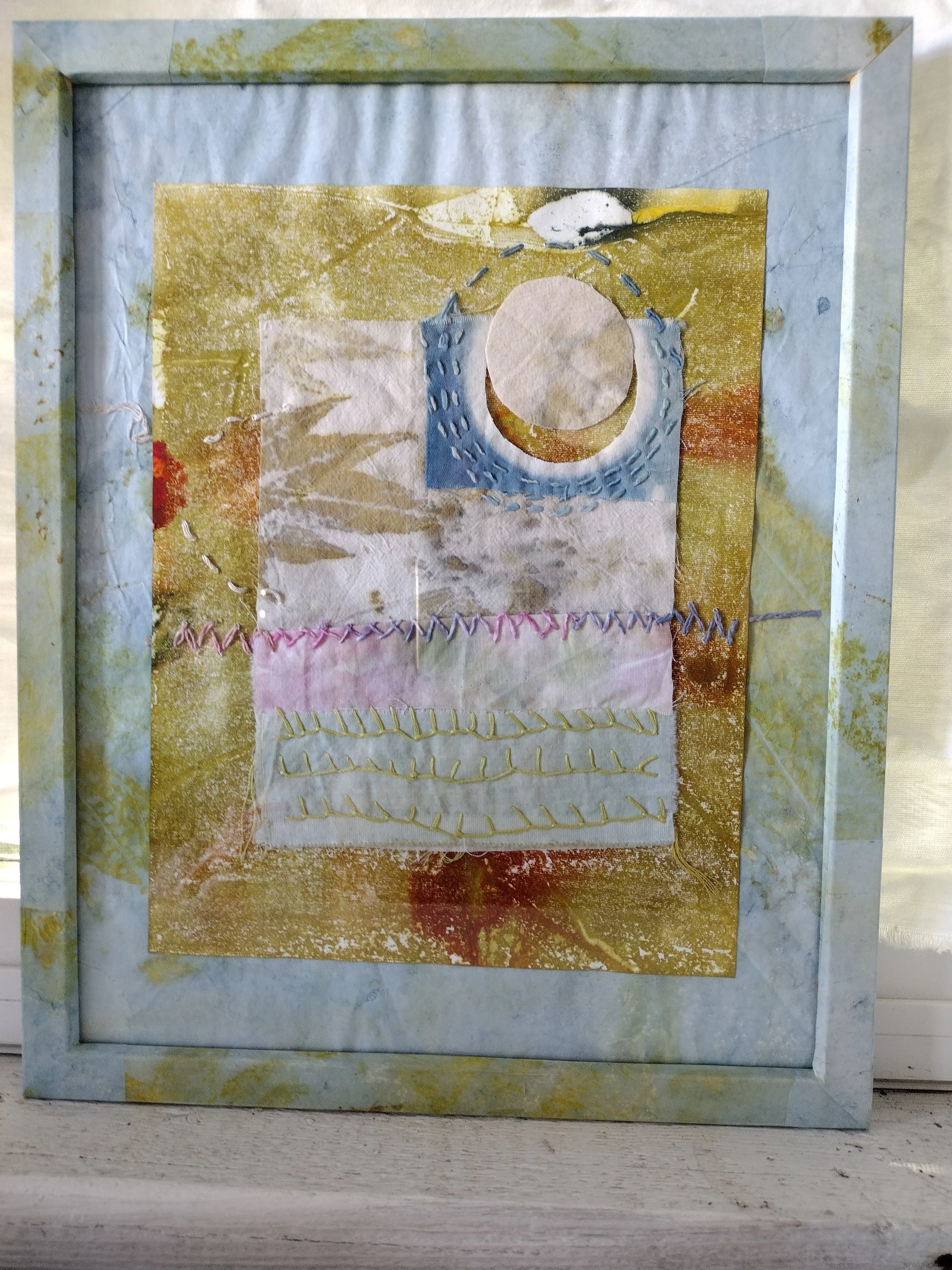 Mixed media artwork featuring layers of textured paper, stitching, and paint in earthy tones, with onlaid fabric and decorative stitching patterns. By Amy Real