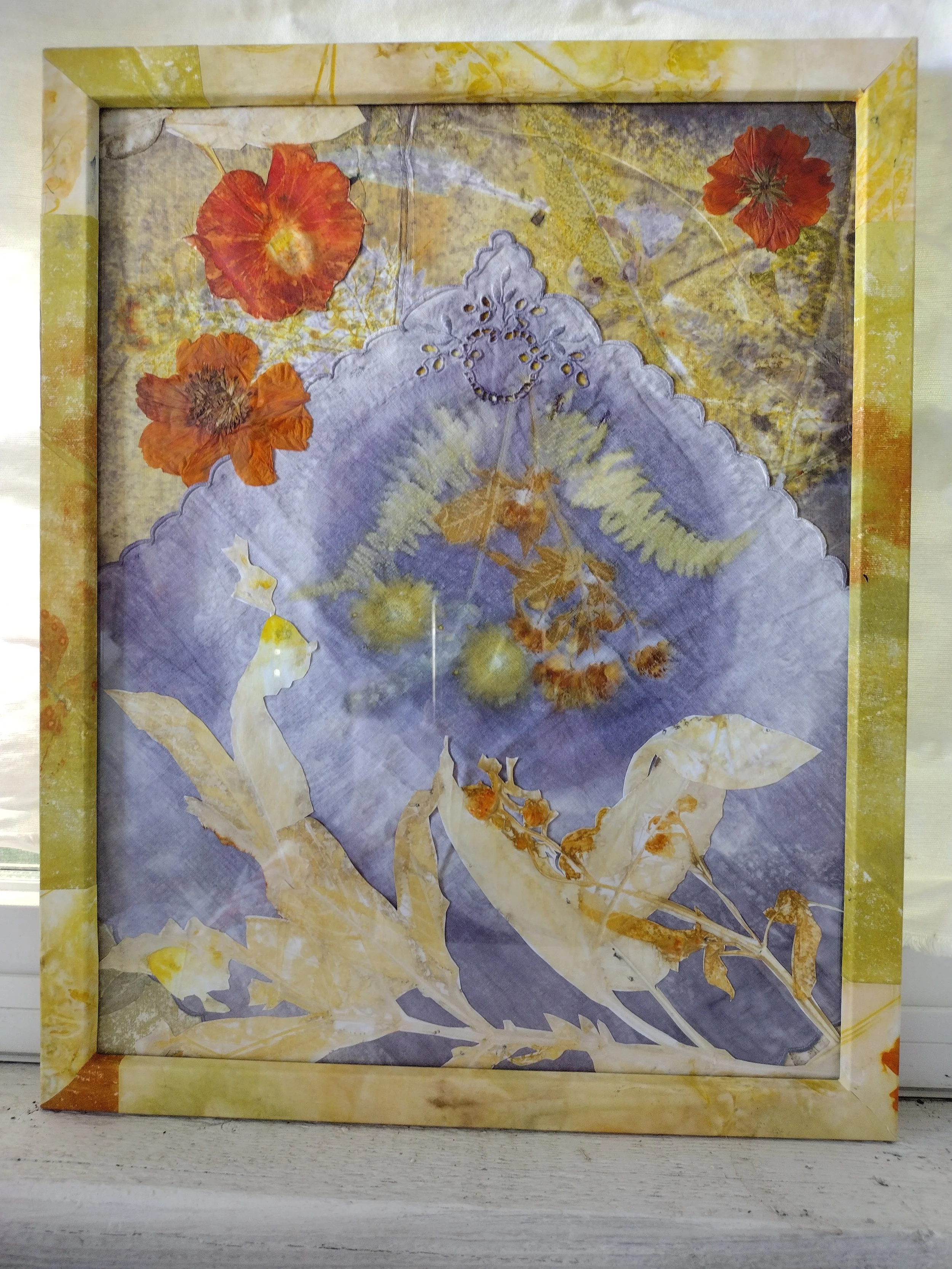 Framed artwork with dried orange and red flowers, against a purple and yellow background, with a decorative border. By Amy Real