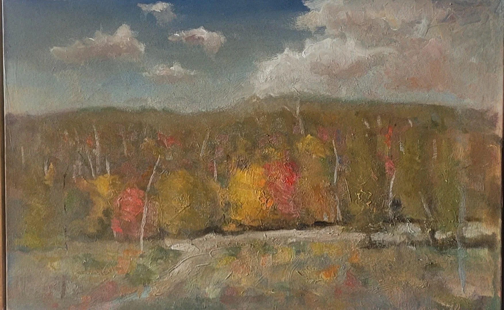 An impressionistic landscape painting of trees with colorful autumn leaves in the foreground, a distant hill or forest in the background, and a partly cloudy sky overhead.  by Patrick Monaghan