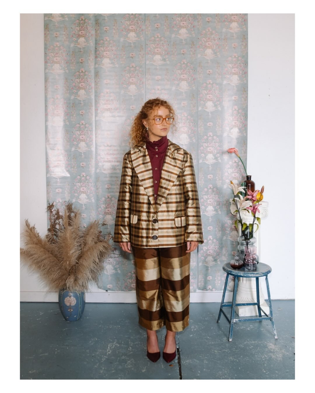 KAVERI
Designed and created by: @abbeygracetuck 

This look features a structured plaid set in warm caramel and cream tones, layered over a burgundy blouse. The blouse features a high ruffled neckline and decorative stitching along the button placket