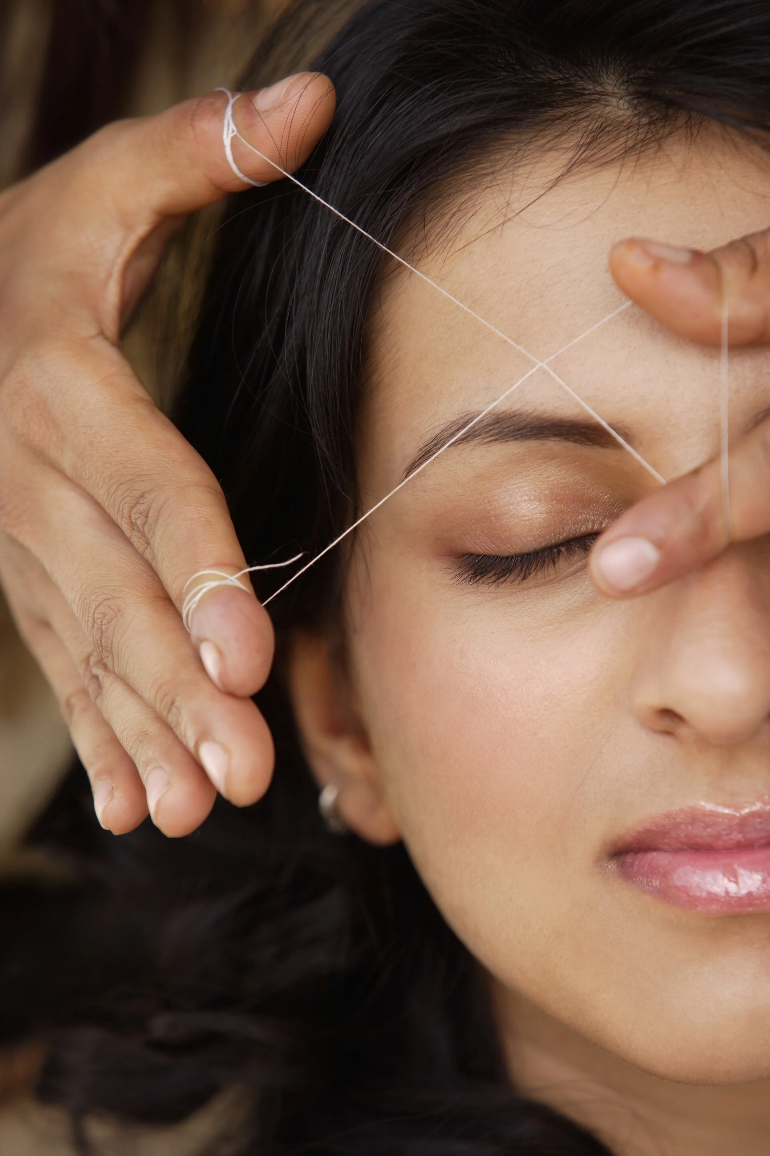 A woman receives a facial acupuncture treatment with fine needles inserted near her forehead.