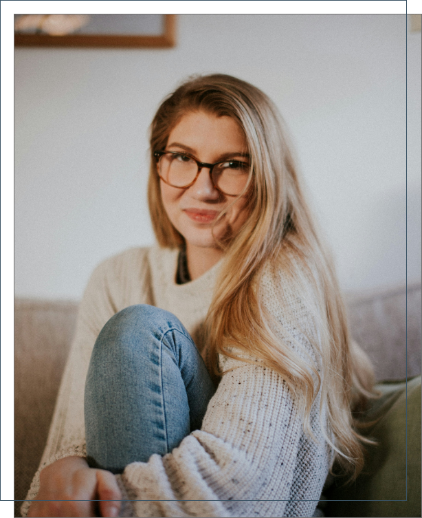 blonde woman with glasses sitting on a couch