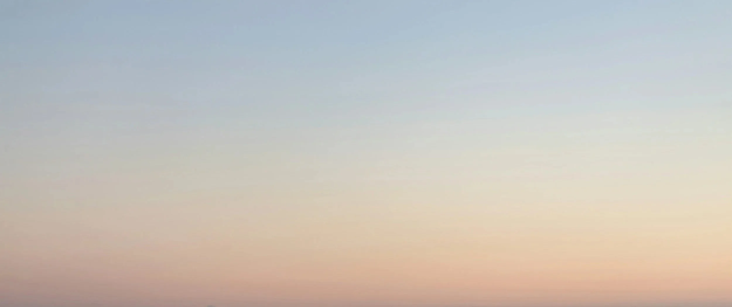 Soft blue-gray sky fading to a warm peach horizon