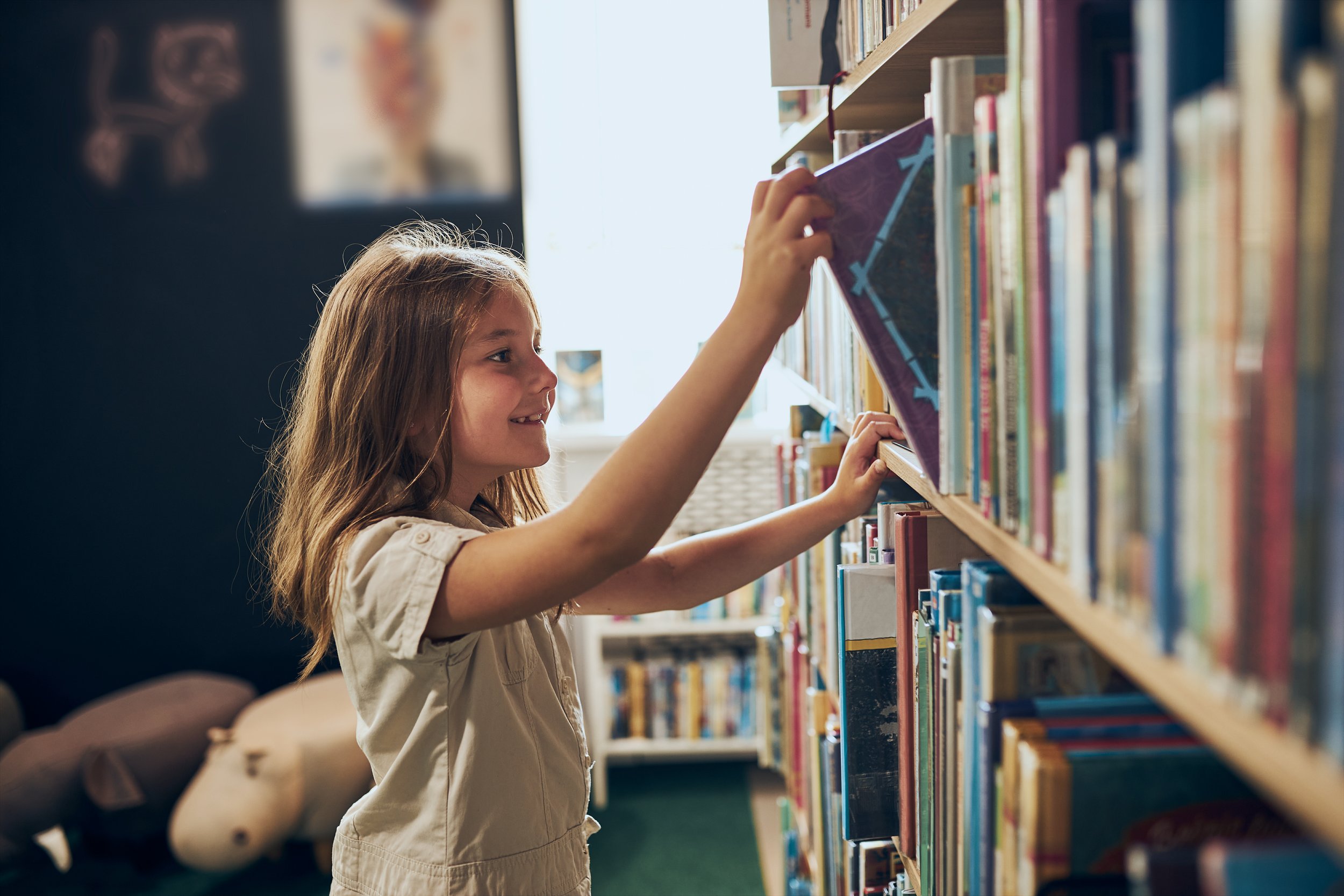 young girl choosing a book to read at the library