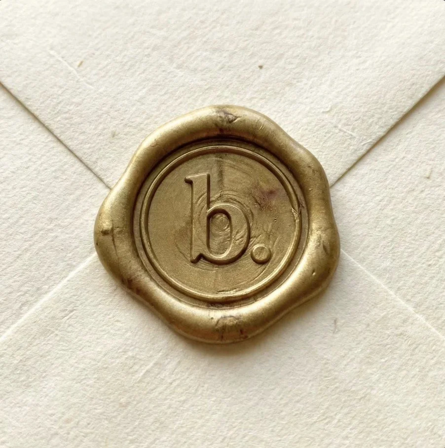 Envelope sealed with gold wax stamp marked with a lowercase 'b'.