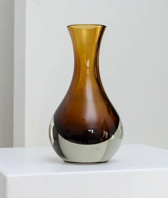 Colorful glass vase with a narrow neck and a wide base, featuring a gradient from amber to dark brown, placed on a white surface. vintage.