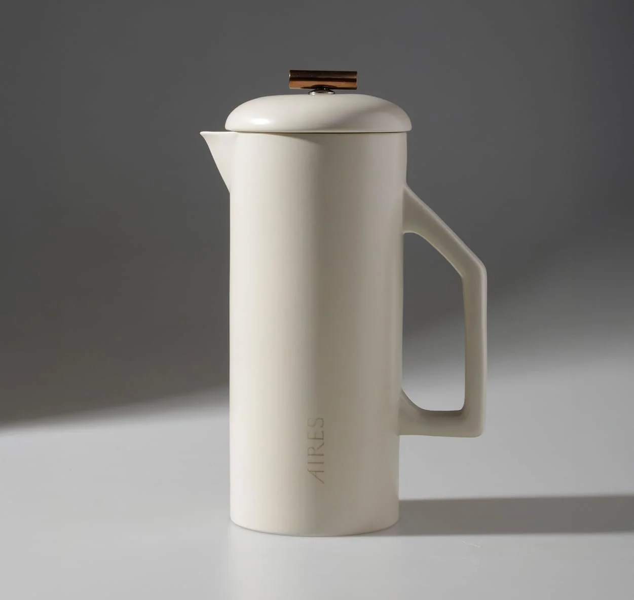 A white ceramic french press with a sleek modern design and a wooden lid