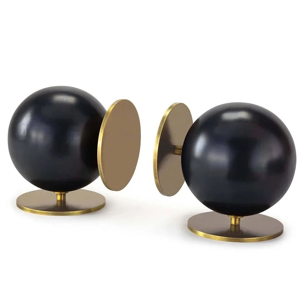 decorative bookends, two black spherical balls mounted on gold-colored bases, with a flat oval plate