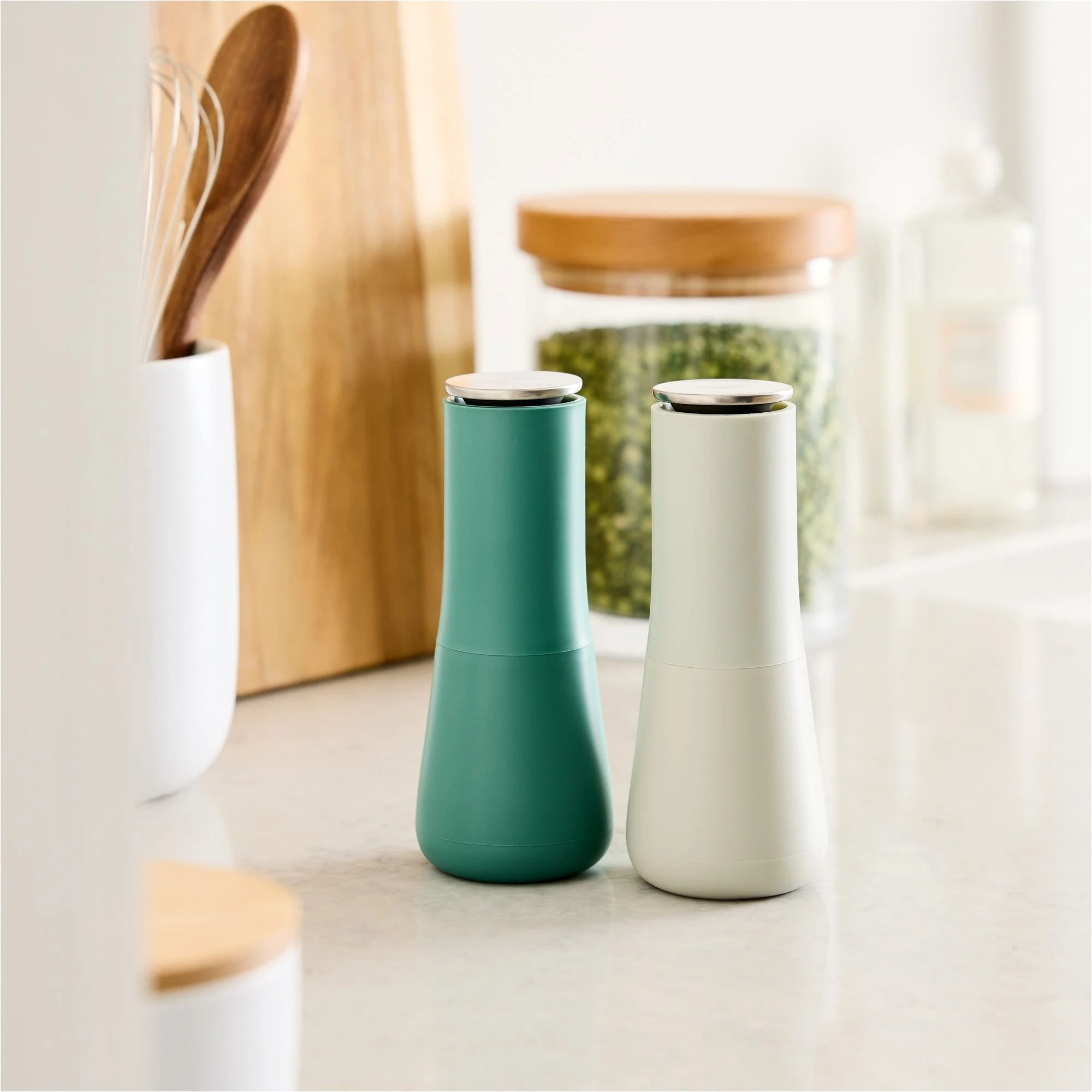 Two modern salt and pepper shakers, one teal and one white.
