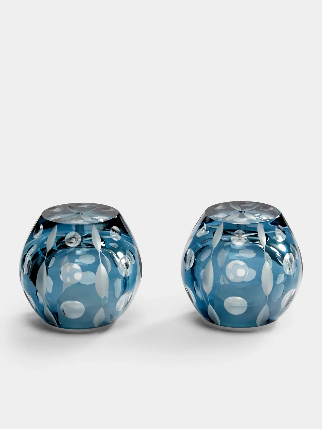 Two blue glass salt and pepper dispensers with white leaf and dot patterns