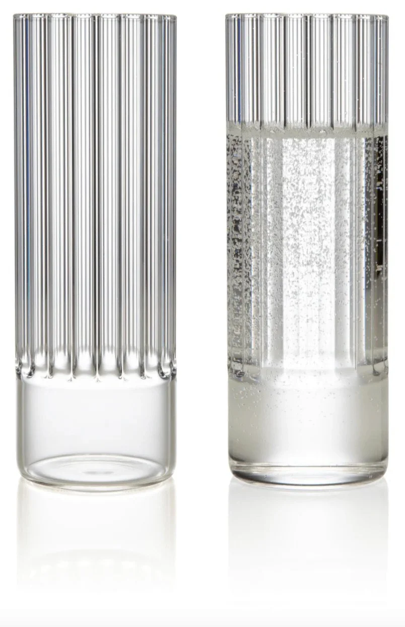 Two glass test tubes, one empty and one filled with a clear, bubbly liquid, both with vertical ridges.