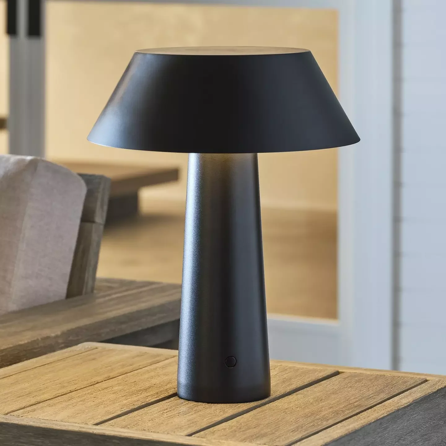 A modern black minimalist cordless table lamp with a conical shade and tapered base