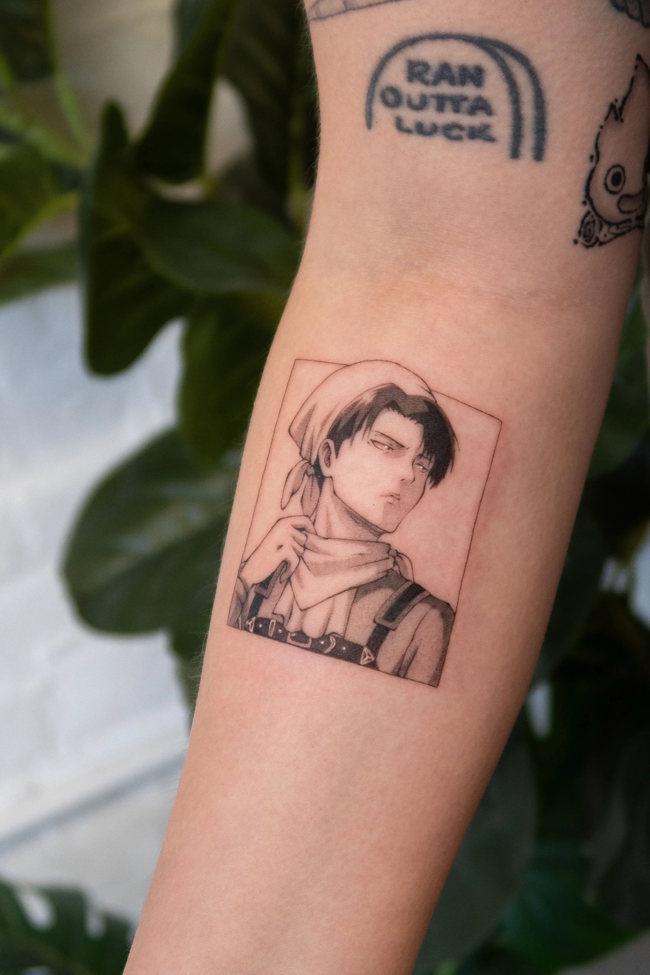 Tattoo of a woman in grayscale with short hair, wearing a bandana, holding a gun, and looking sideways.