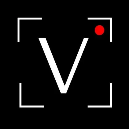 White letter 'V' with a small red dot beside it on a black background