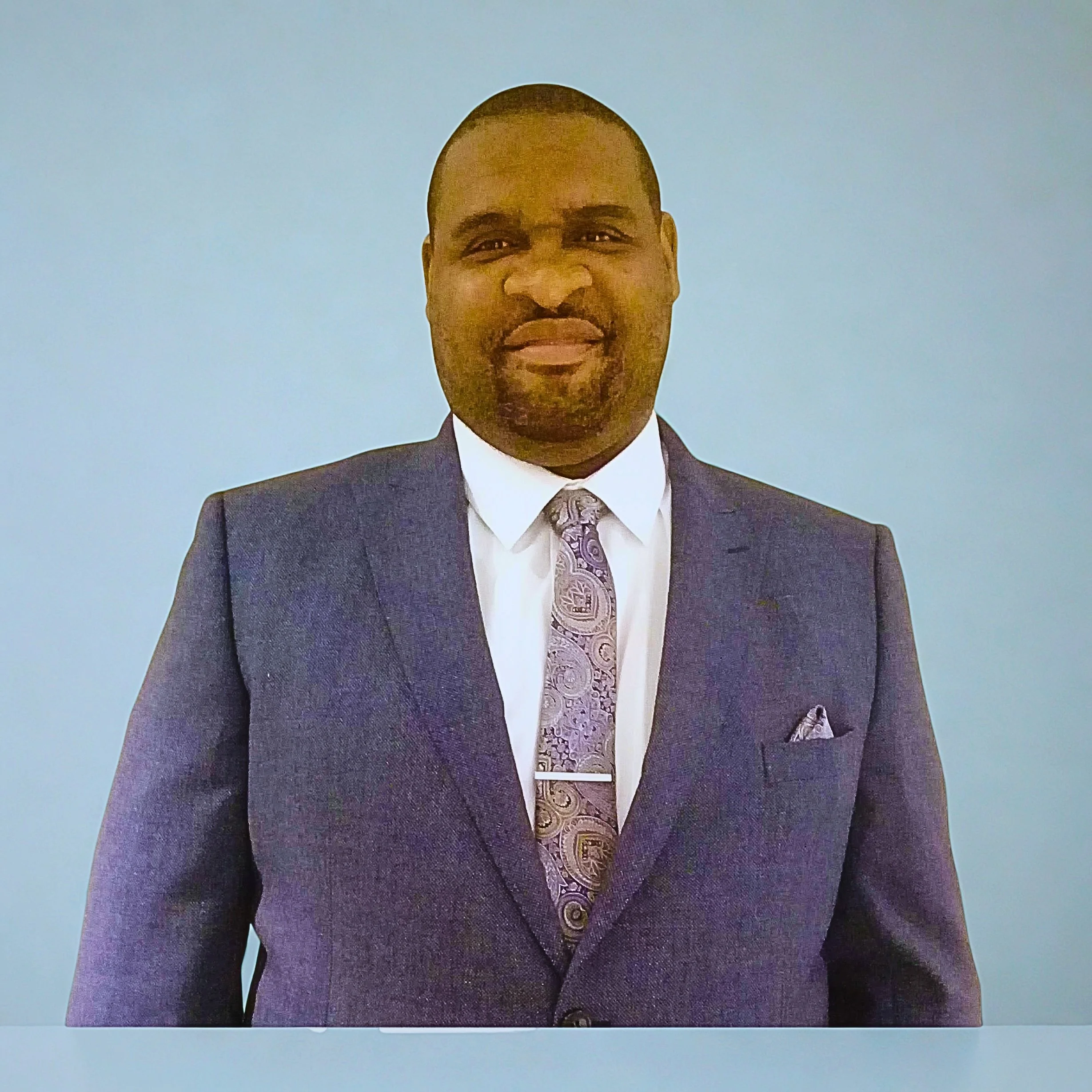 Icon of a person sitting at a desk with a paper and a clock showing the time as 3 o'clock, indicating office or work setting.