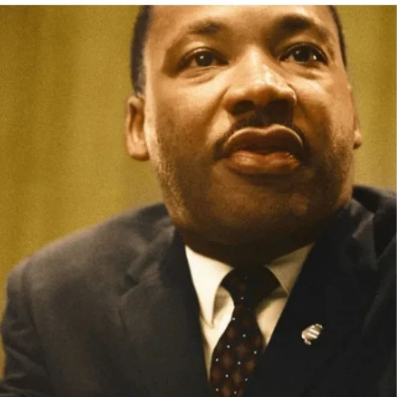Close-up of a man wearing a suit and tie, looking slightly to the side.