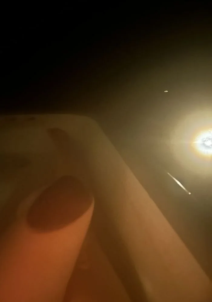 Digital Photo by Little Door. Self Portrait. Close up of knee reflection in the water of an outfoor bath in the candlelight in front of a glowing light in a dark environment.